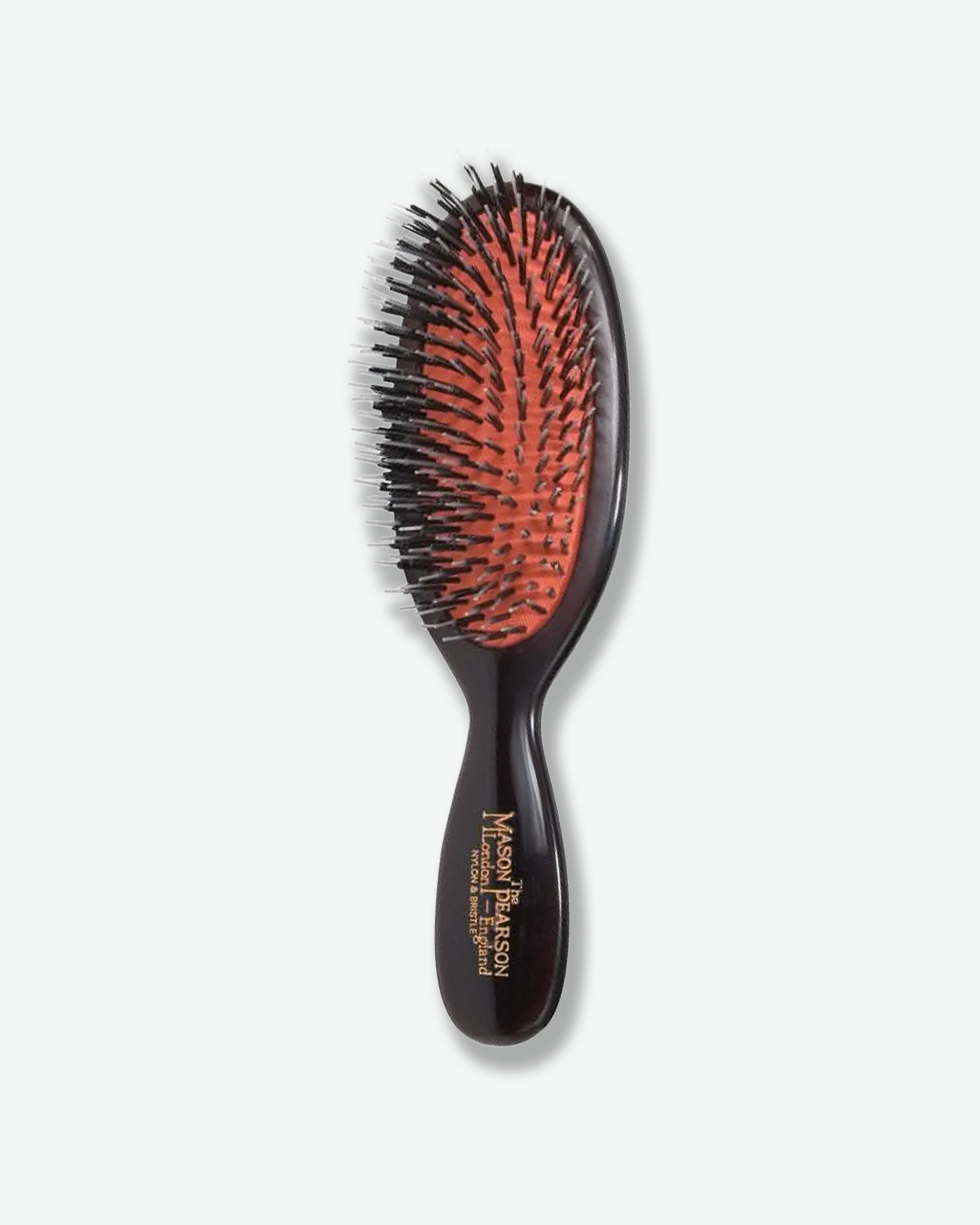 Front view of a Mason Pearson classic dark ruby oval hairbrush featuring a bright orange rubber cushion with a mixture of black nylon and boar bristles, and gold text on the handle reading "The Mason Pearson London - England Nylon & Bristle".