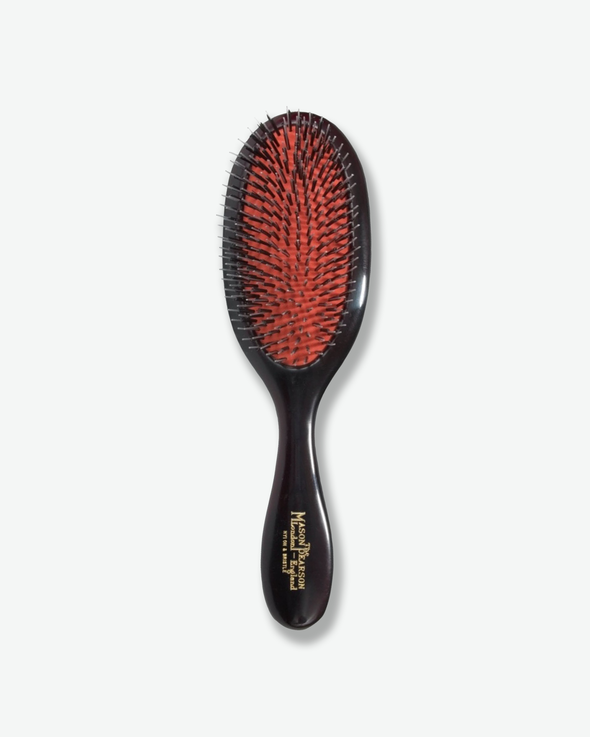 Front view of a Mason Pearson classic dark ruby oval hairbrush featuring a bright orange rubber cushion with a mixture of black nylon and boar bristles, and gold text on the handle reading "The Mason Pearson London - England Nylon & Bristle".