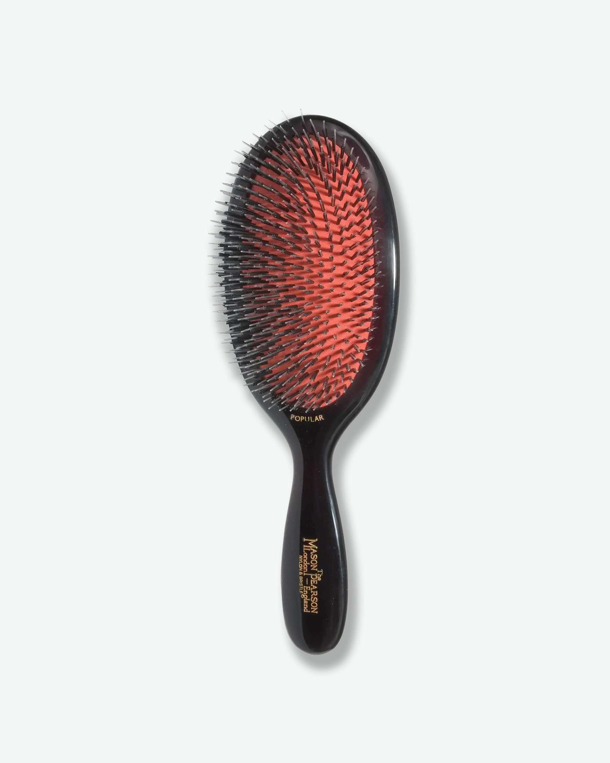 Front view of a Mason Pearson classic dark ruby oval hairbrush featuring a bright orange rubber cushion with a mixture of black nylon and boar bristles, and gold text on the handle reading "The Mason Pearson London - England Nylon & Bristle".