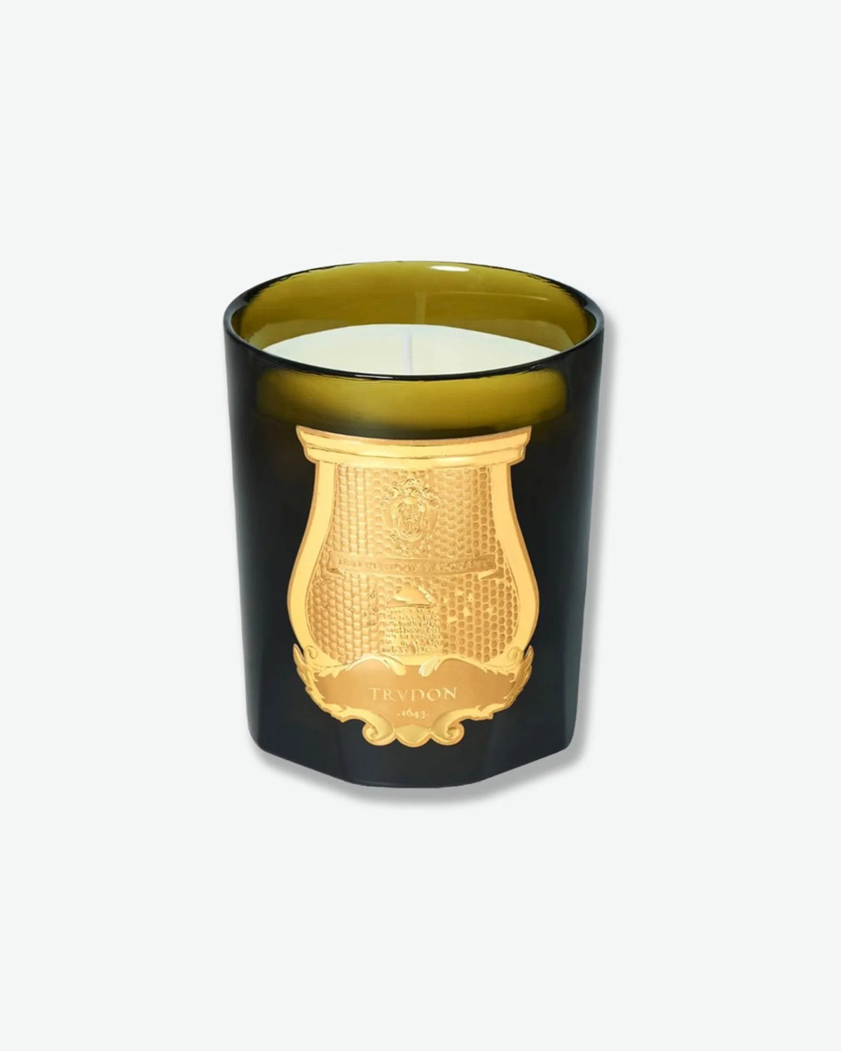 Trudon scented candle in a dark green glass vessel with an ornate gold emblem.