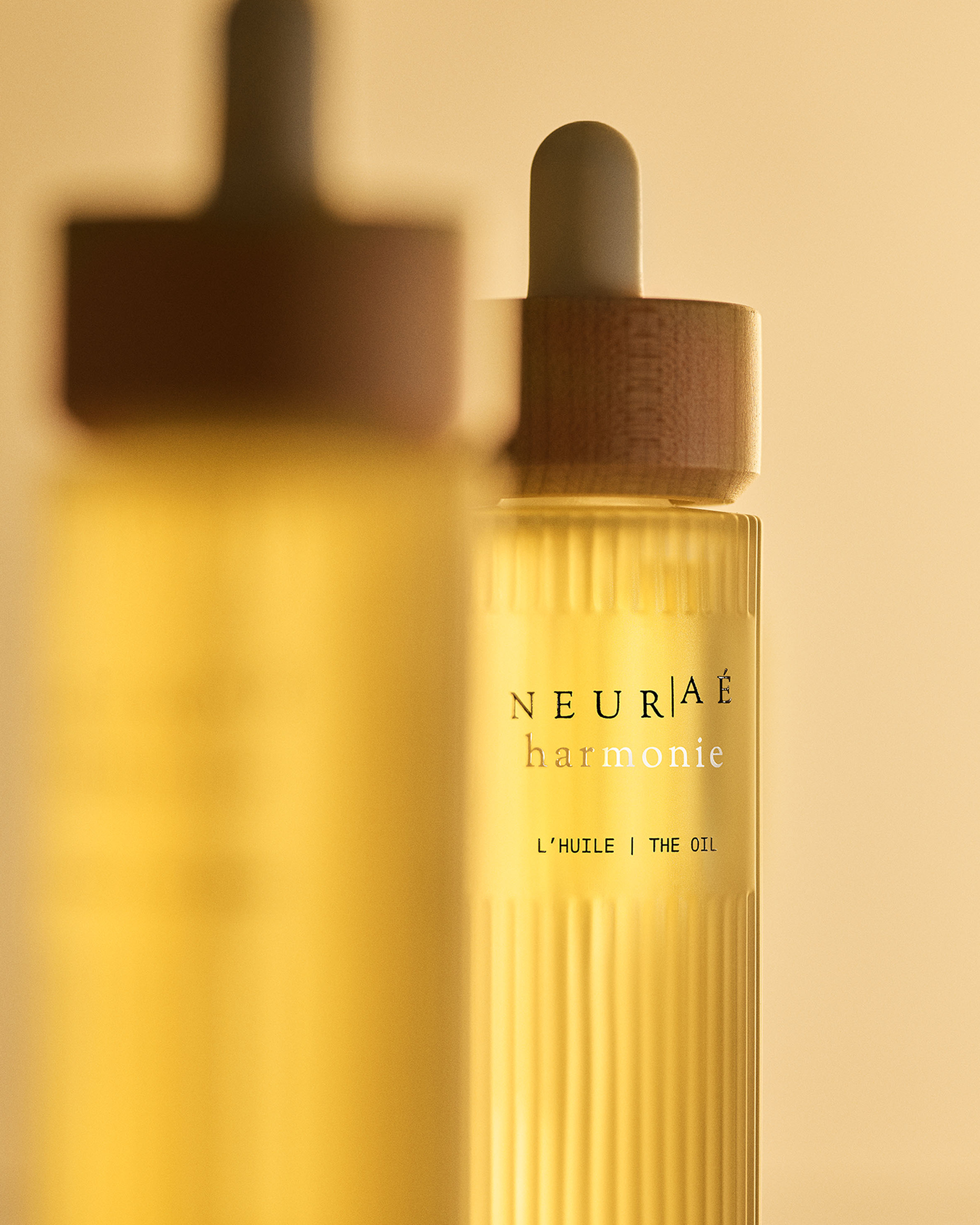 Neuráé harmonie oil bottle with wooden dropper on a beige background