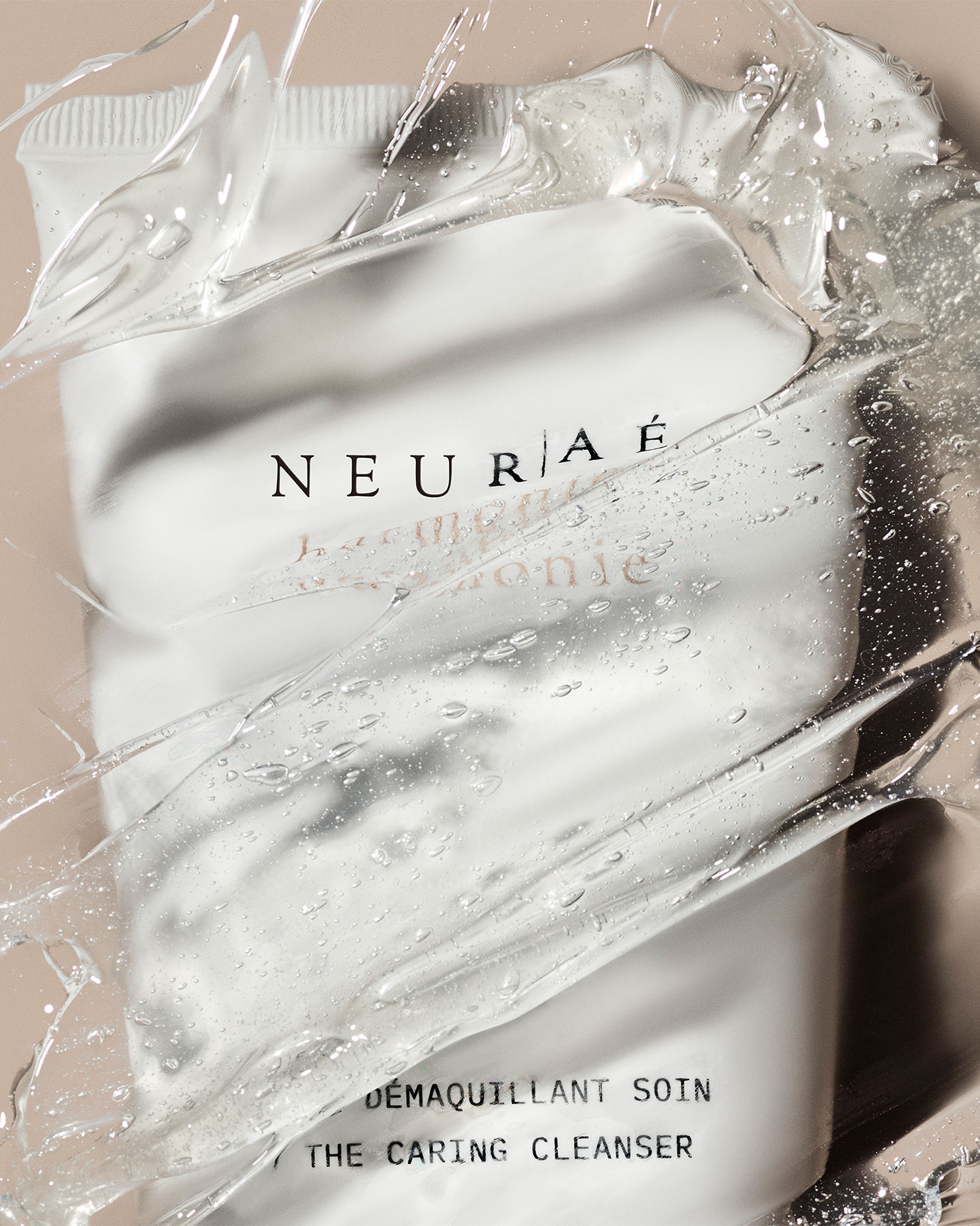 A stylized close-up shot of the Neurae The Caring Cleanser white tube seen through a thick, glossy layer of clear gel texture.