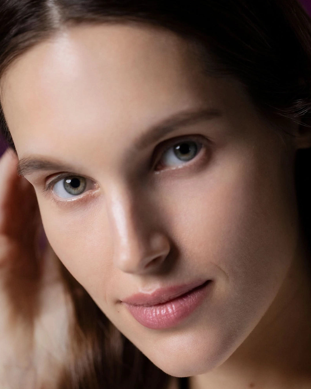 Close-up of a person with a neutral expression, softly lit.