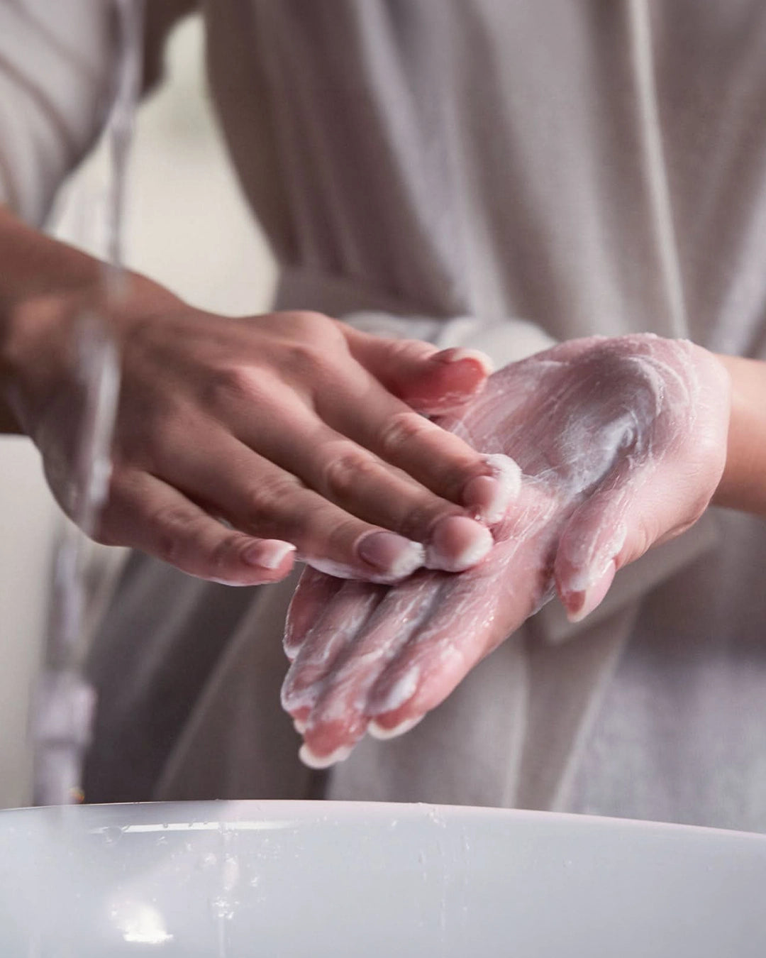 Person with mixing powder on her hand under running water