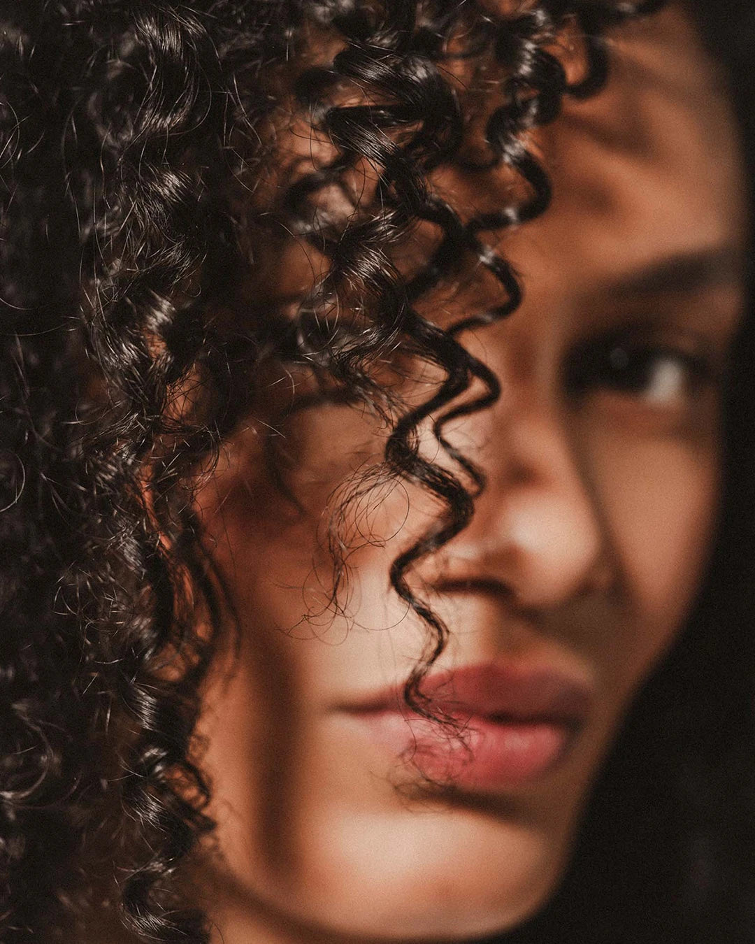 Close-up of a person with curly hair, blurred background