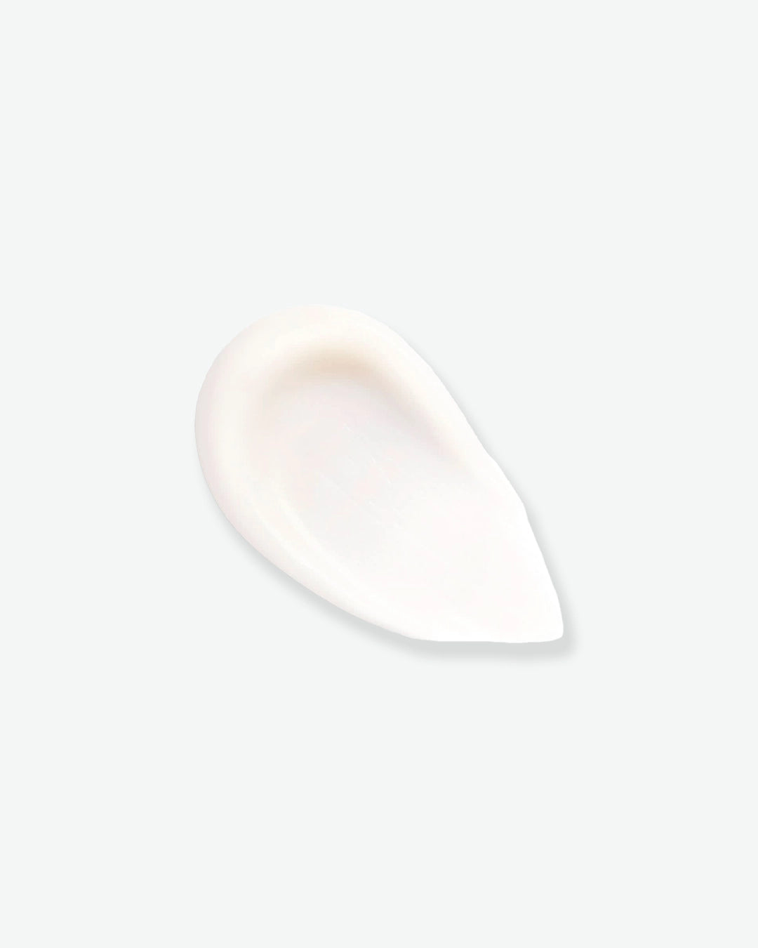 A smooth, thick teardrop-shaped swipe of creamy white makeup primer showcasing its soft matte texture against a light background.