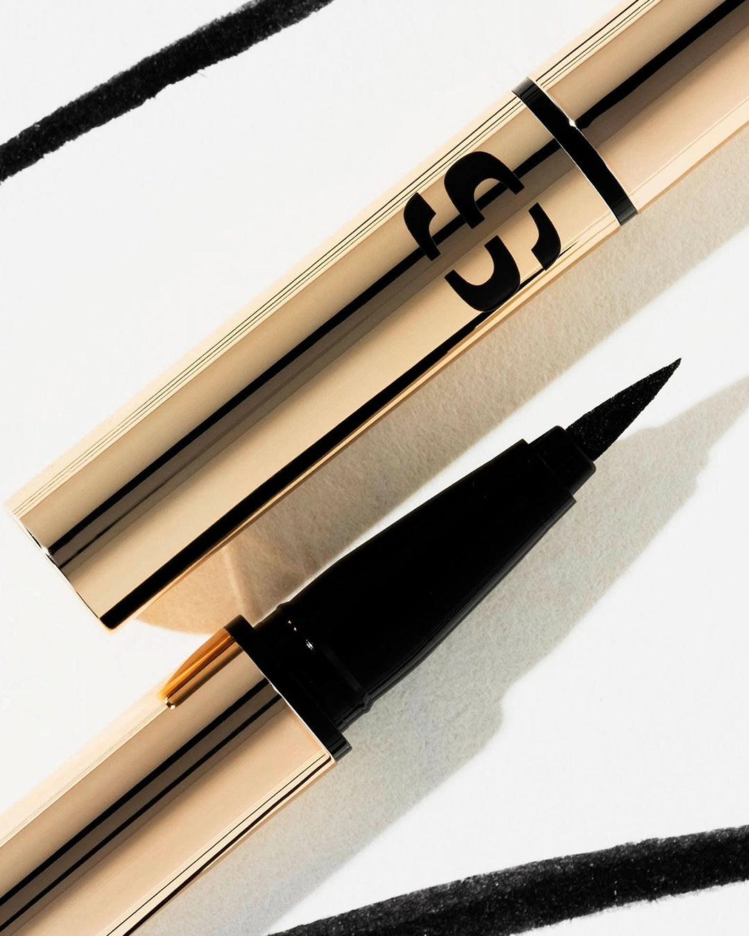 Eyeliner with gold casing and black tip on a white background