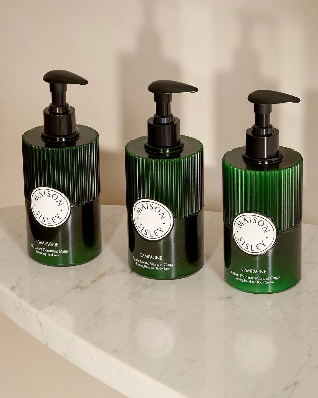 Three green bottles with pump dispensers on a marble surface