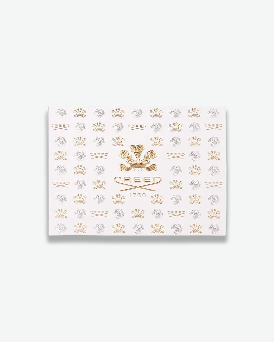 White product packaging box embossed with gold and silver 'Creed' logos pattern on a white background
