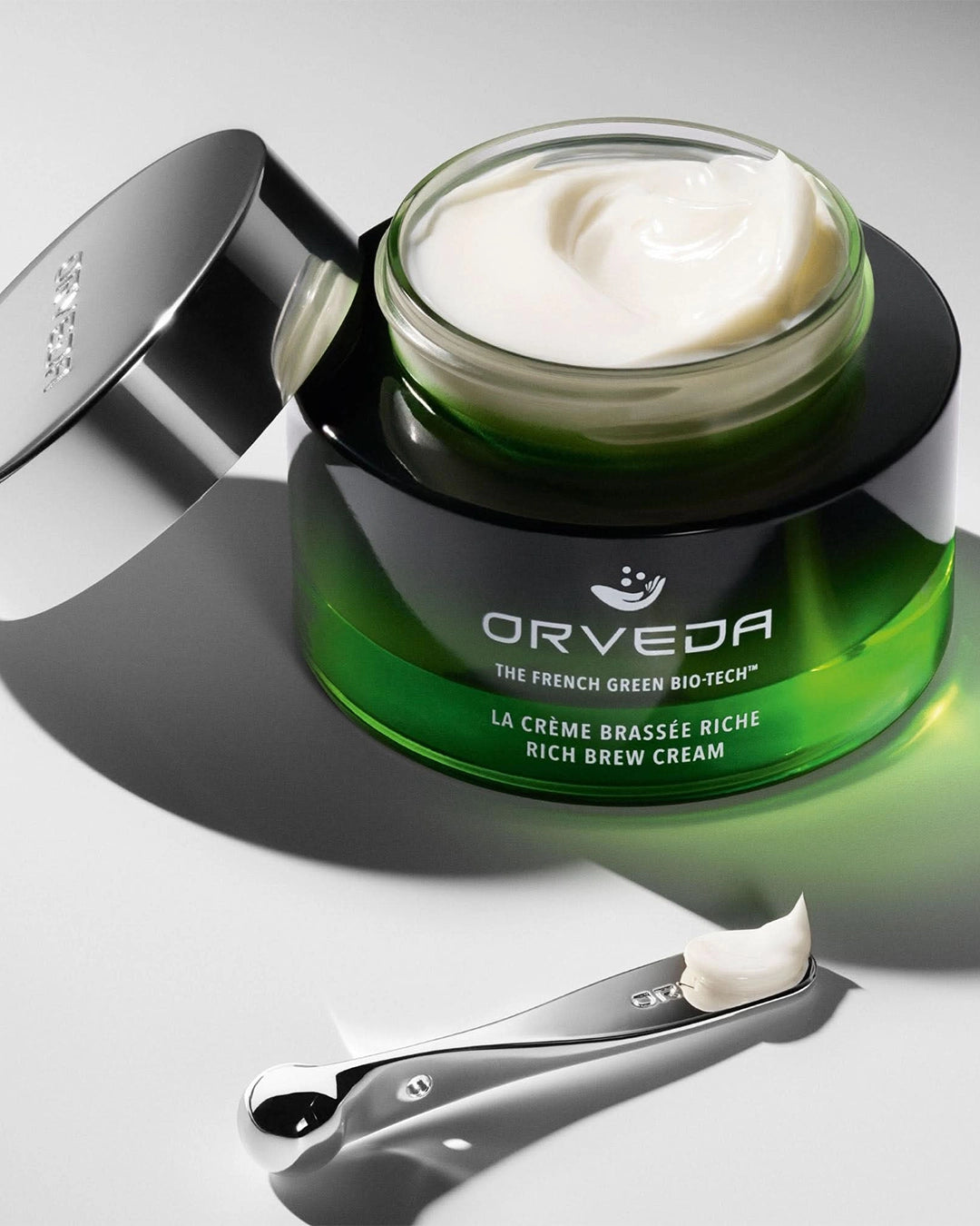 Orveda cream jar with applicator on a gray background