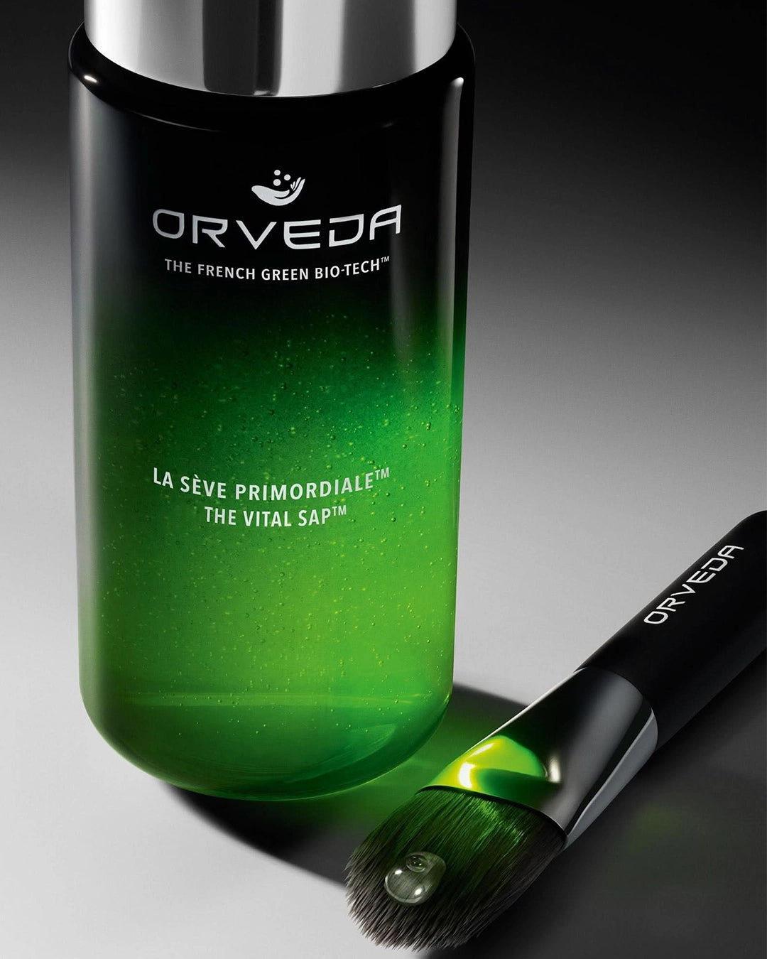 Orveda green skincare product with a brush on a dark background