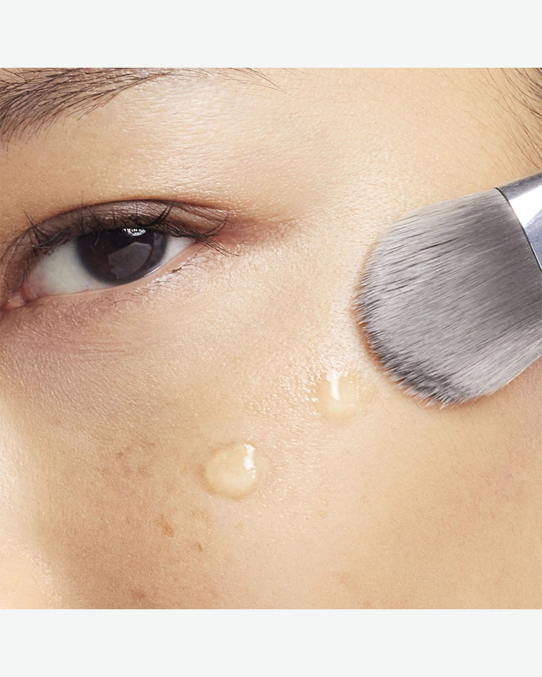 Close-up of a makeup brush applying product to a person's face