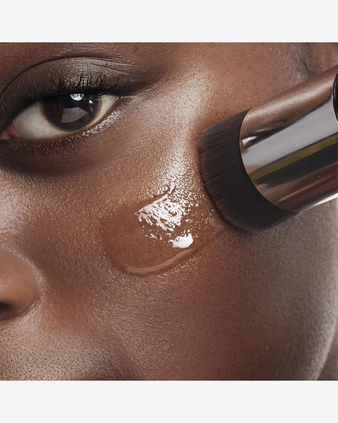 Close-up of a person applying makeup with a brush to their face.