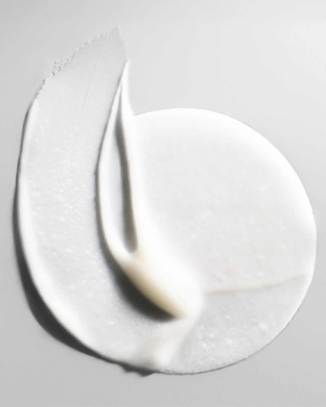 Close-up of a white cream or paint swatch on a gray background
