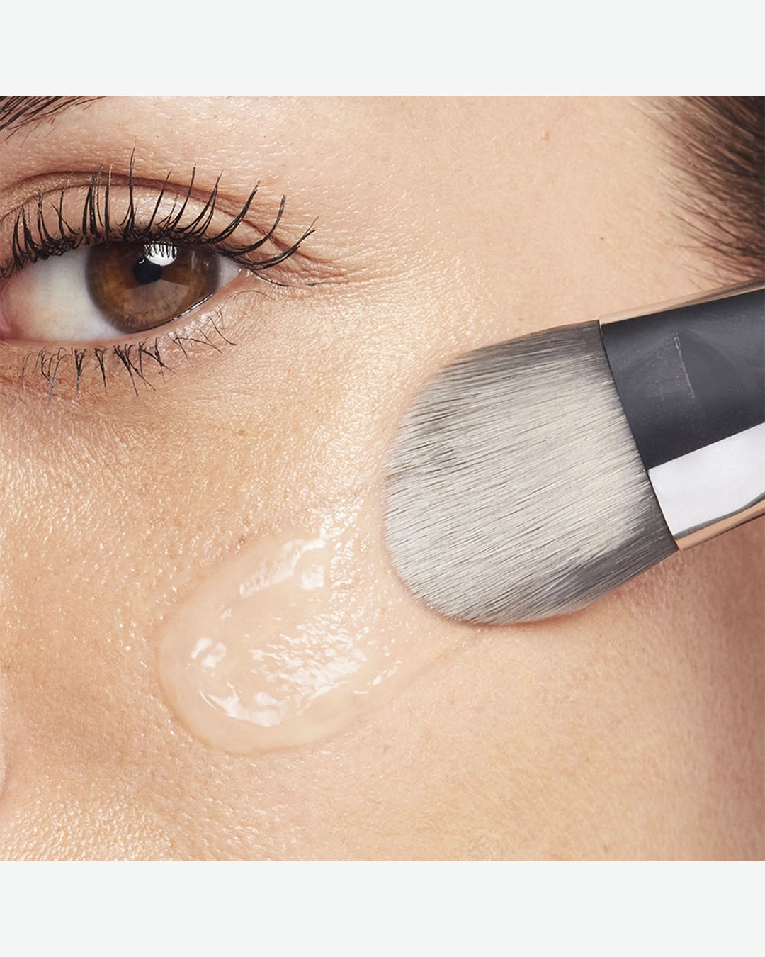 Makeup brush applying cream to a person's face