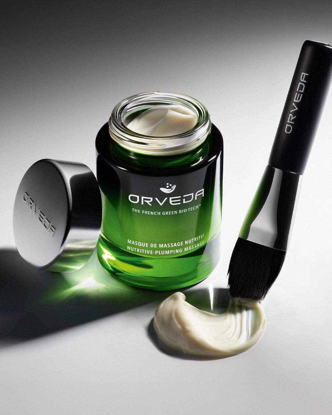 Orveda skincare product with green jar and applicator on a gray background