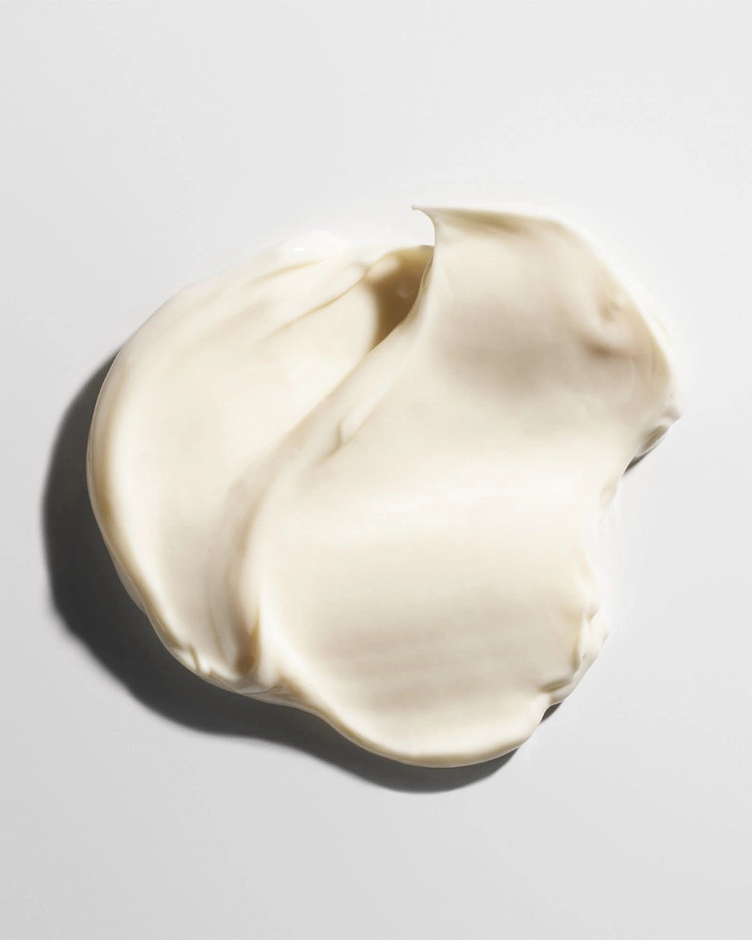 Swirl of white cream on a light gray background