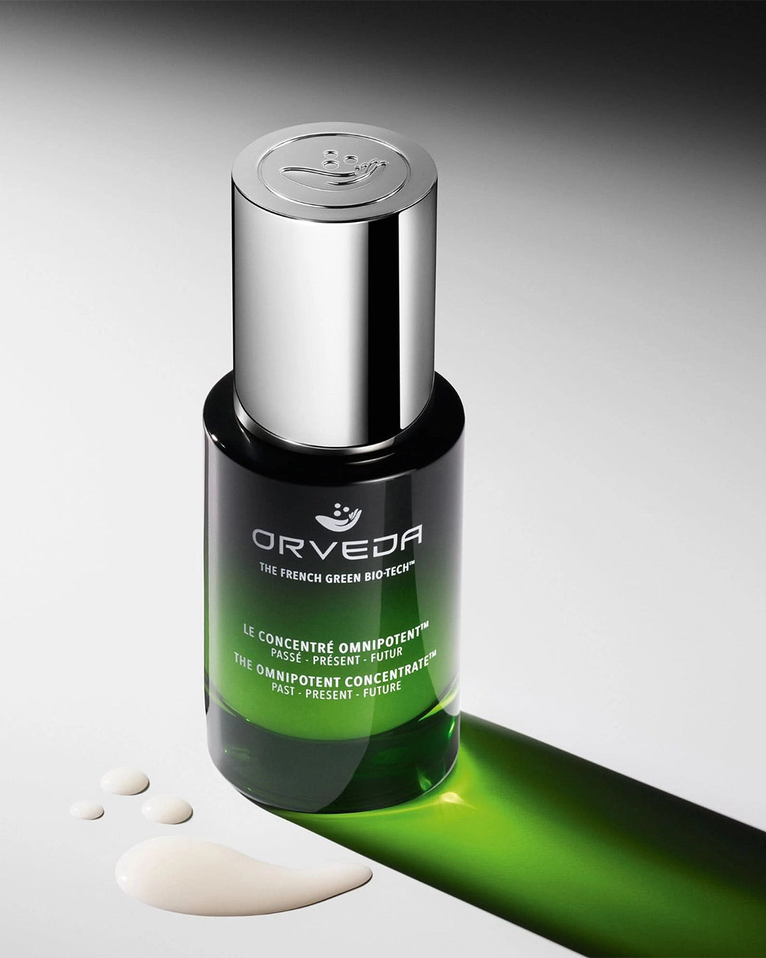 Orveda skincare serum bottle with green liquid on a gray background