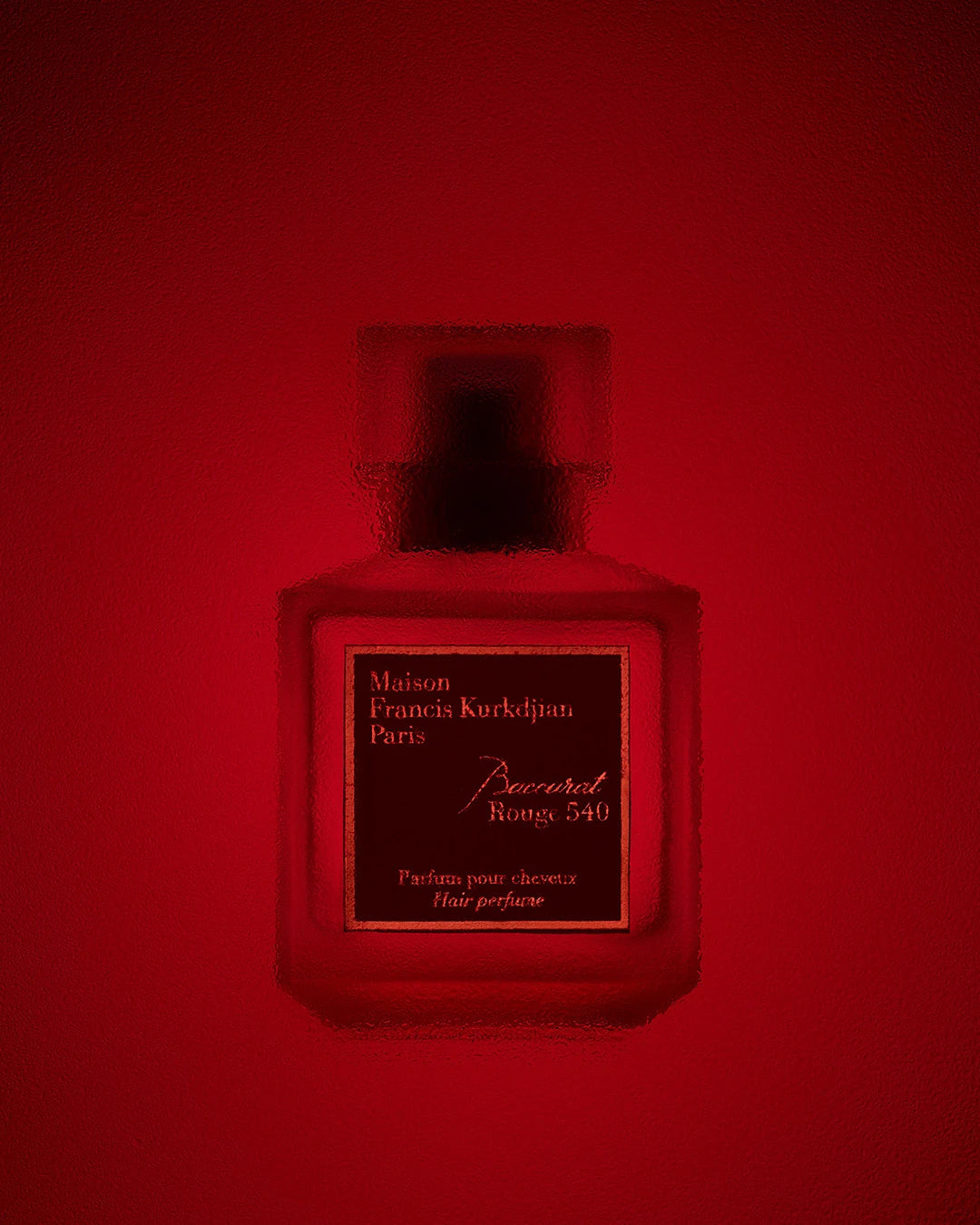 Hair perfume bottle with 'Maison Francis Kurkdjian' on a red background
