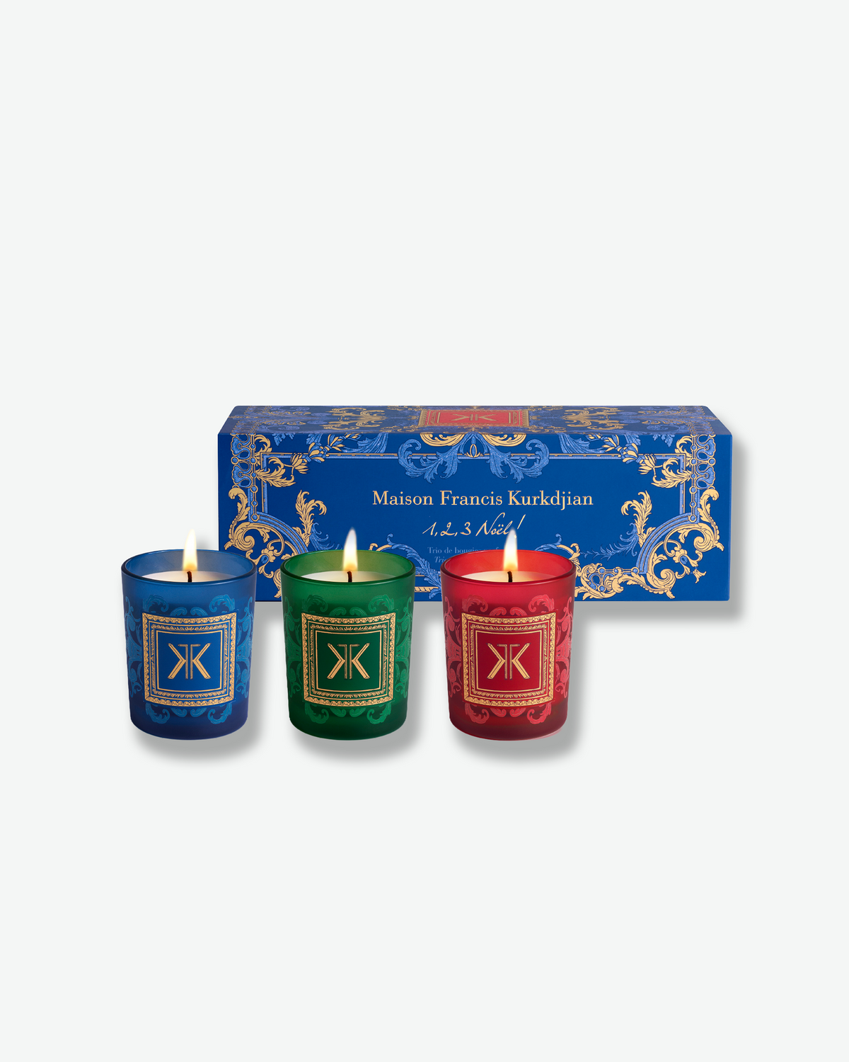 Maison Francis Kurkdjian holiday candle trio featuring three lit candles in blue, green, and red glass with decorative gold accents.