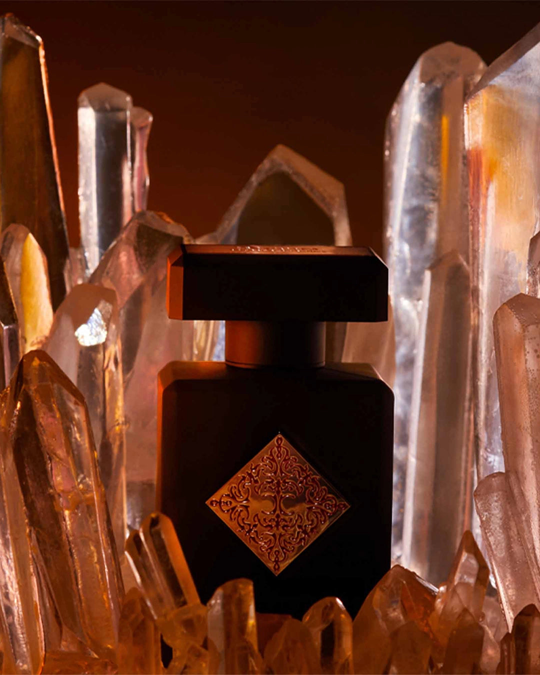 Black perfume bottle with decorative design in front of crystal-like structures