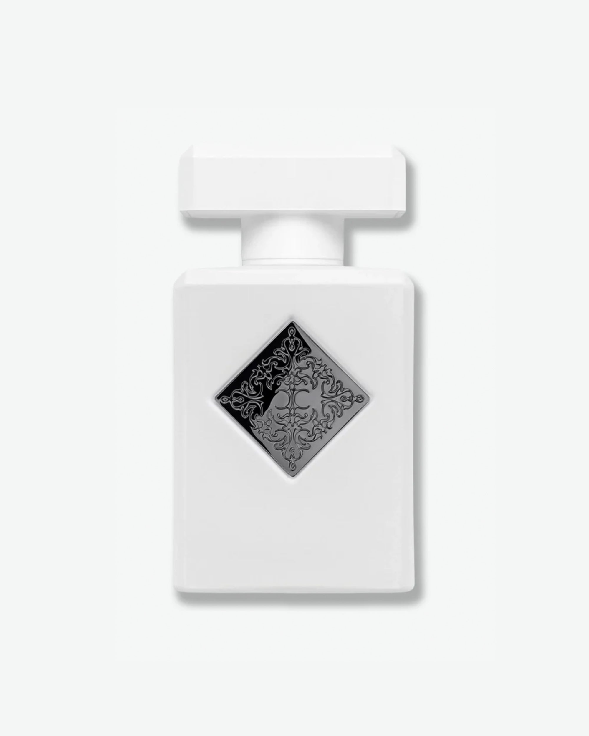 Initio Parfums Privés fragrance in a minimalist matte white square bottle, featuring a centered silver-toned diamond badge with a detailed engraved emblem, isolated on a light grey background.