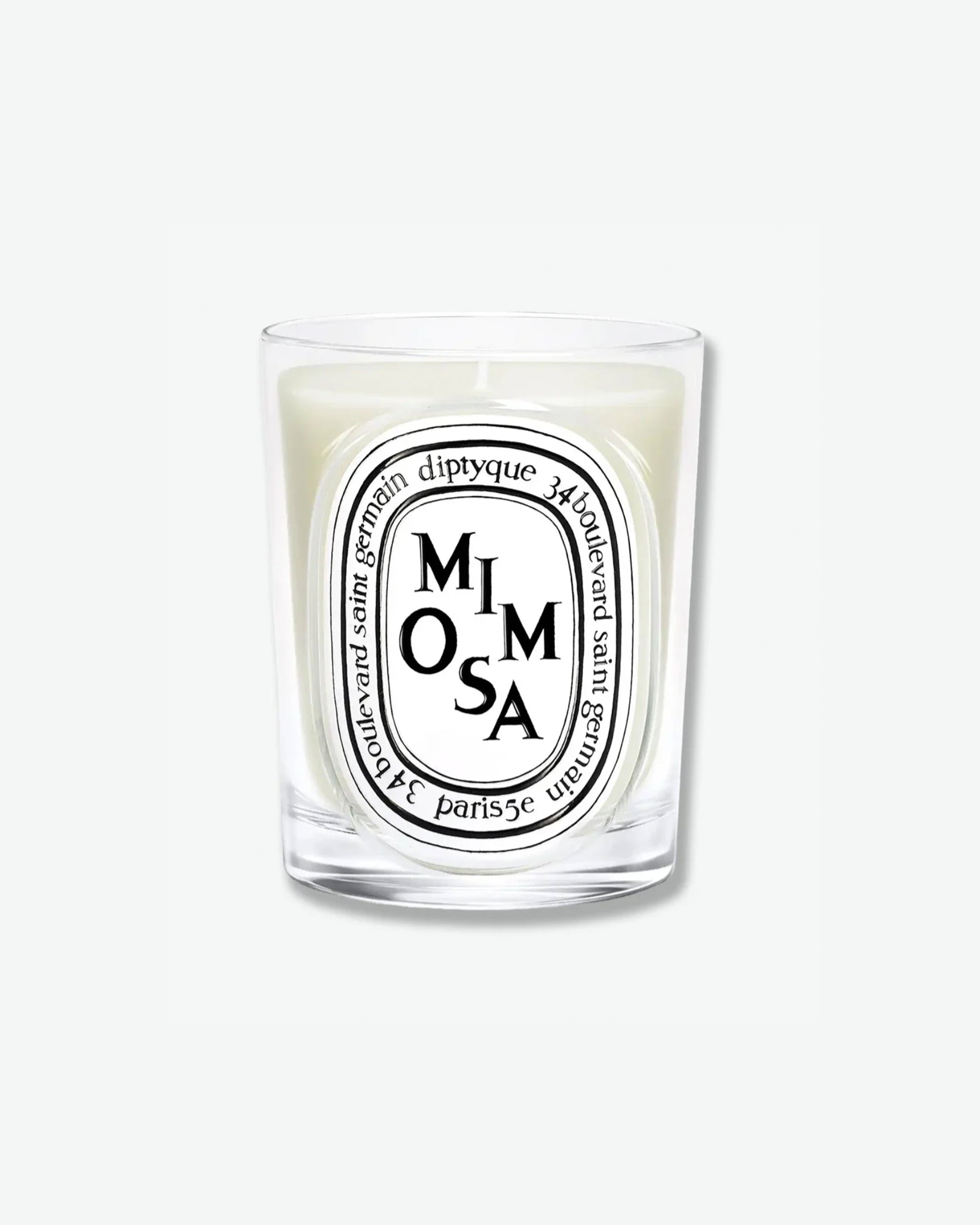 Diptyque Mimosa scented candle in a classic clear glass jar featuring the signature white oval logo with black lettering, isolated on a light grey background.