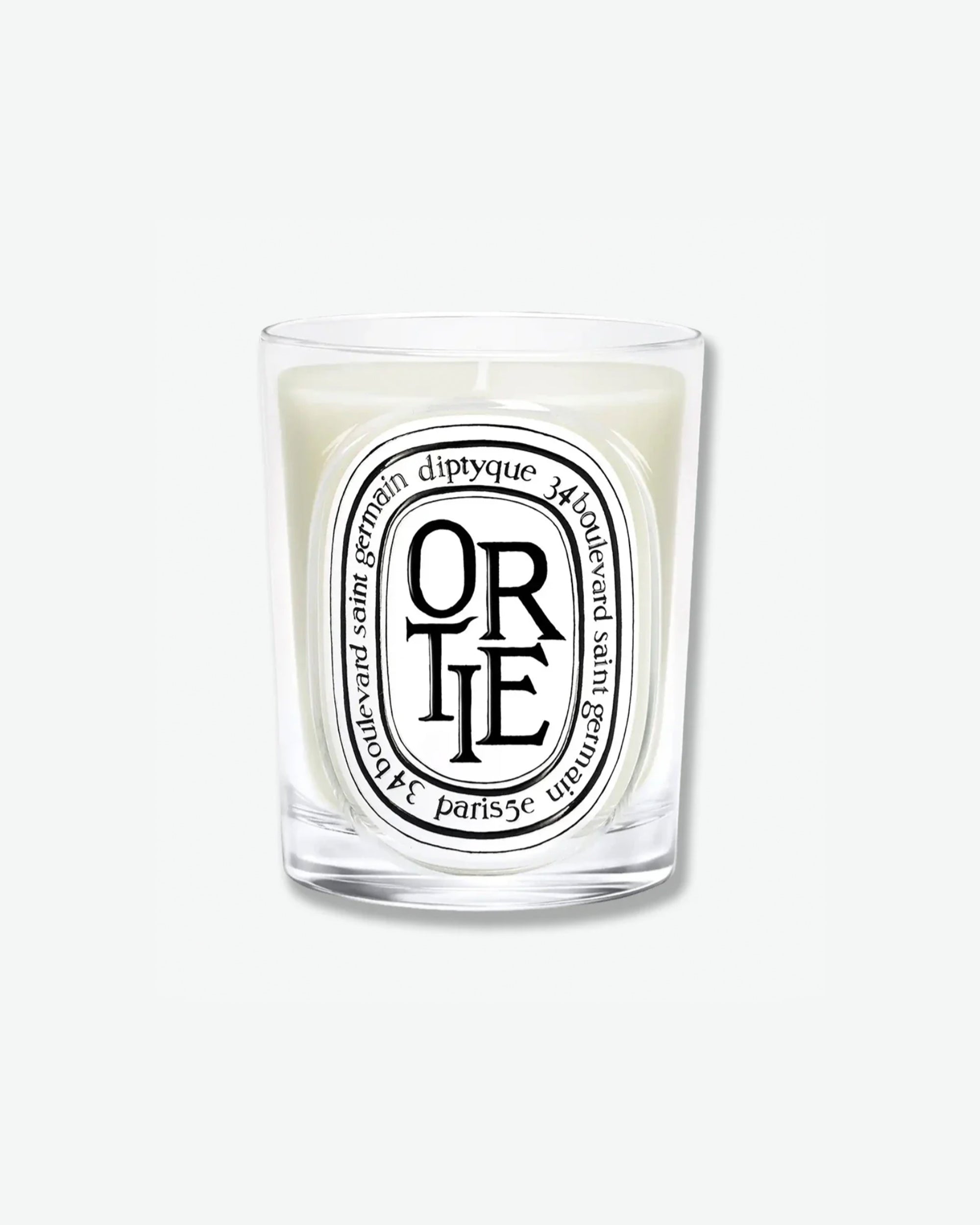 Diptyque Ortie scented candle in a classic clear glass jar featuring the signature white oval logo with black lettering, isolated on a light grey background.