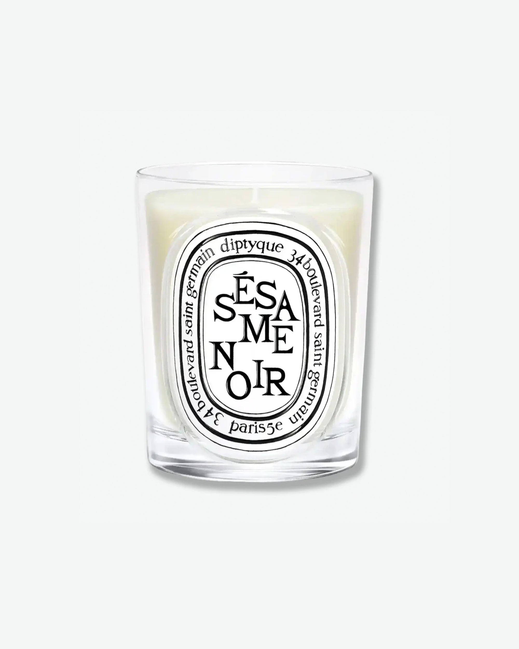 Diptyque Sésame Noir scented candle in a classic clear glass jar featuring the signature white oval logo with black lettering, isolated on a light grey background.