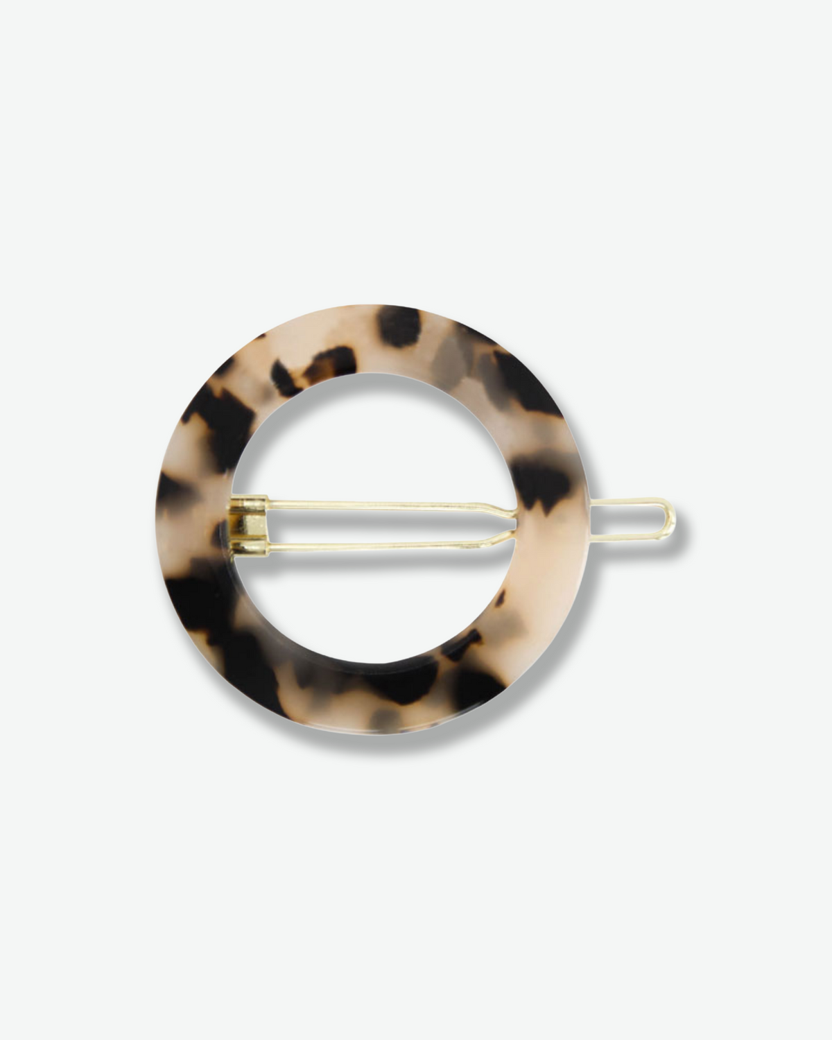 Circular Bachca Paris hair pin featuring a glossy beige and black tortoiseshell pattern with a slender gold-tone fastening prong, displayed against a white background.