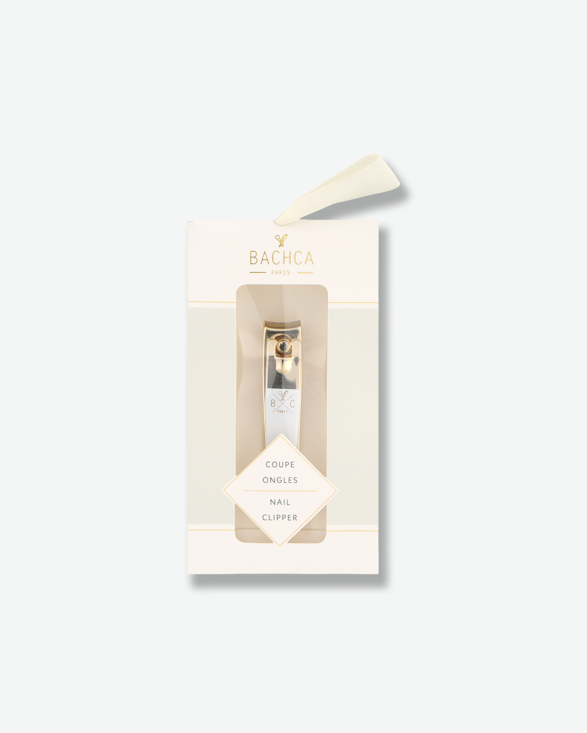 Luxury gold and white nail clipper in its elegant cream-colored retail packaging on a white background.