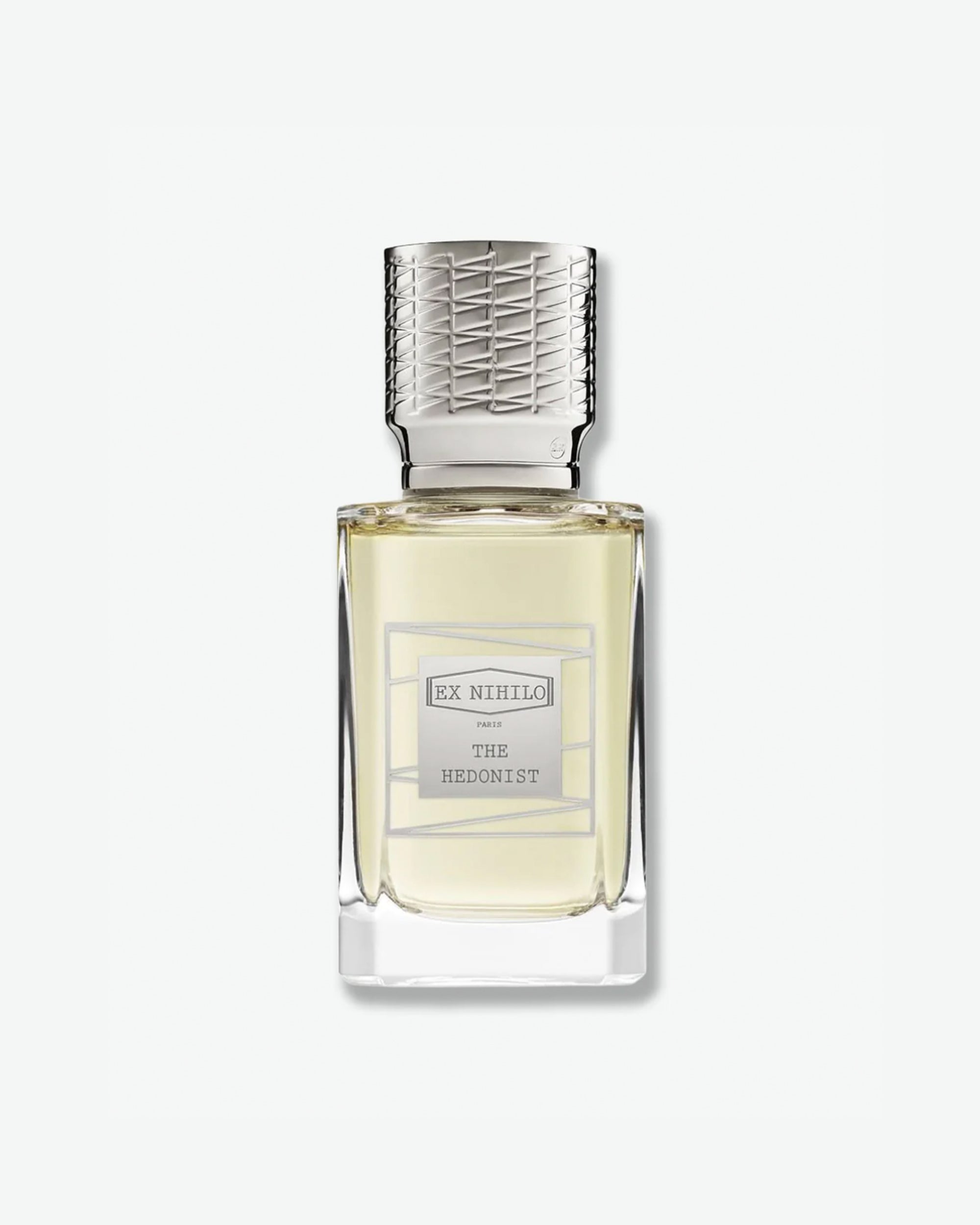Ex Nihilo The Hedonist Eau de Parfum in a heavy clear glass bottle showcasing a pale chartreuse liquid, topped with an intricately engraved silver cap and a matching silver geometric label, isolated on a light grey background.