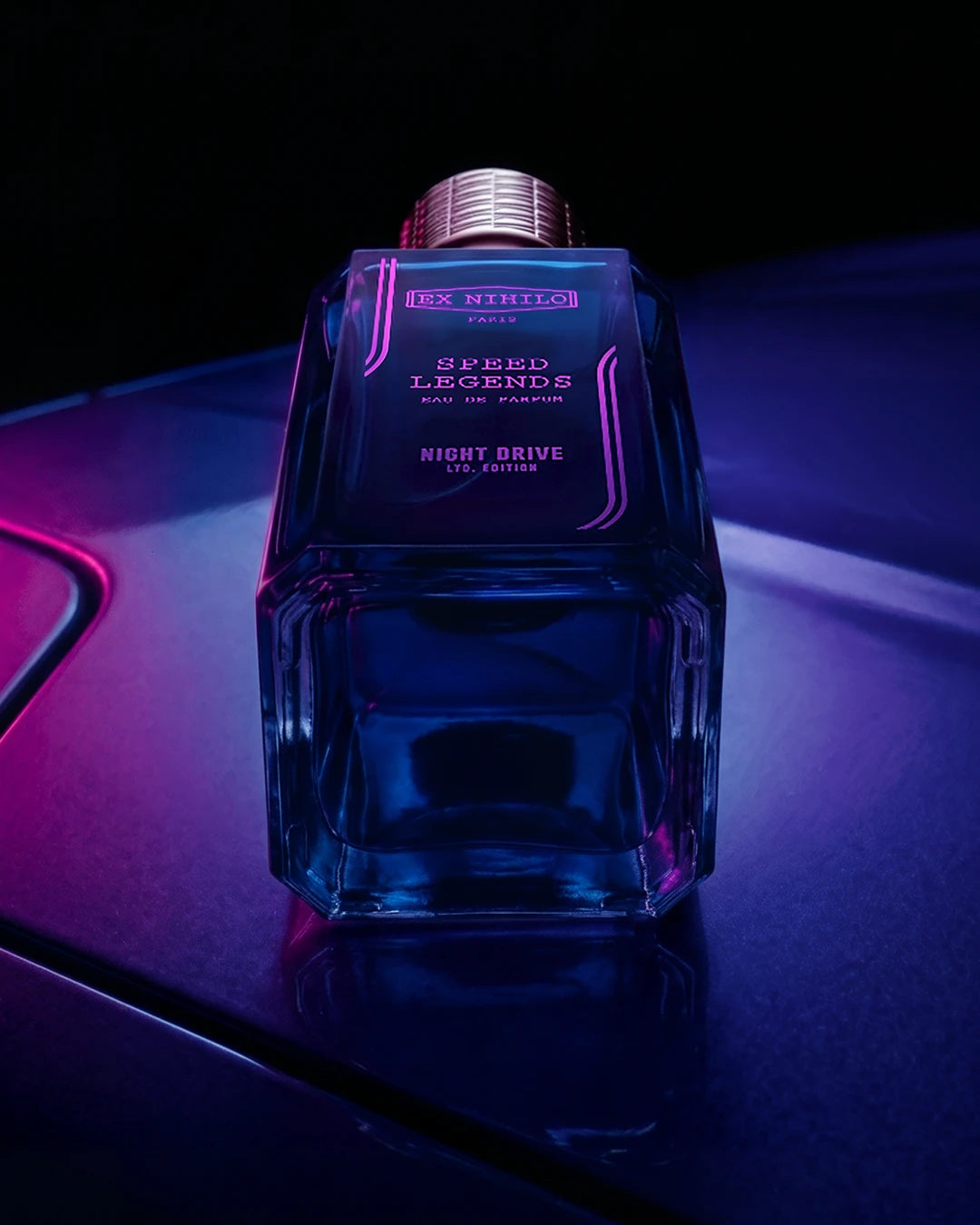 Blue perfume bottle with purple text on a dark background