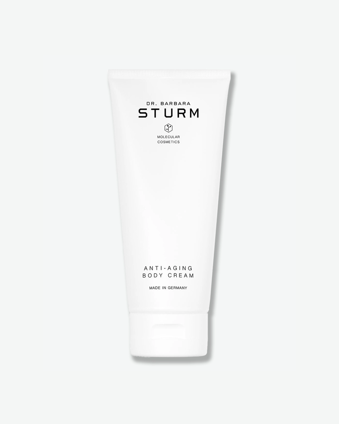 A product shot of a Dr. Barbara Sturm Anti-Aging Body Cream tube, centered against a light gray background. The large, smooth white plastic squeeze tube stands upright on its matching white flip-top cap. The front features black text reading "ANTI-AGING BODY CREAM" and "MADE IN GERMANY".