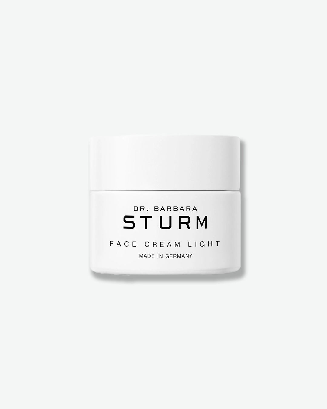 A product shot of a Dr. Barbara Sturm Face Cream Light jar, centered against a light gray background. The white cylindrical skincare jar is topped with a matching flat cap and features black typography on the front that reads "FACE CREAM LIGHT" and "MADE IN GERMANY".