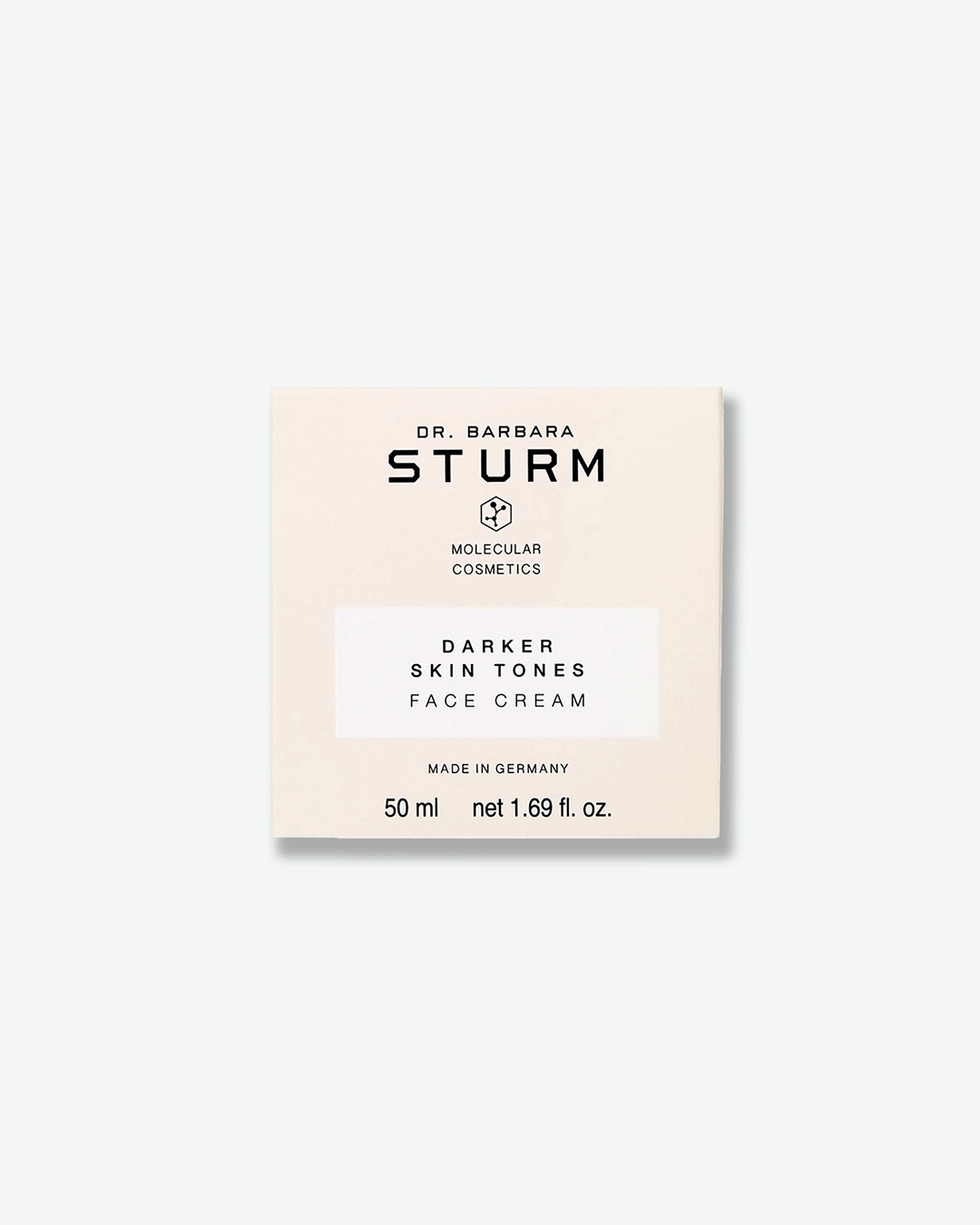 A product shot of the cream-colored square cardboard box for Dr. Barbara Sturm Darker Skin Tones Face Cream, centered against a light gray background. It features clean black branding, a small molecular hexagon logo, and a white rectangular section highlighting the product name. The bottom shows "MADE IN GERMANY" and the volume "50 ml net 1.69 fl. oz."