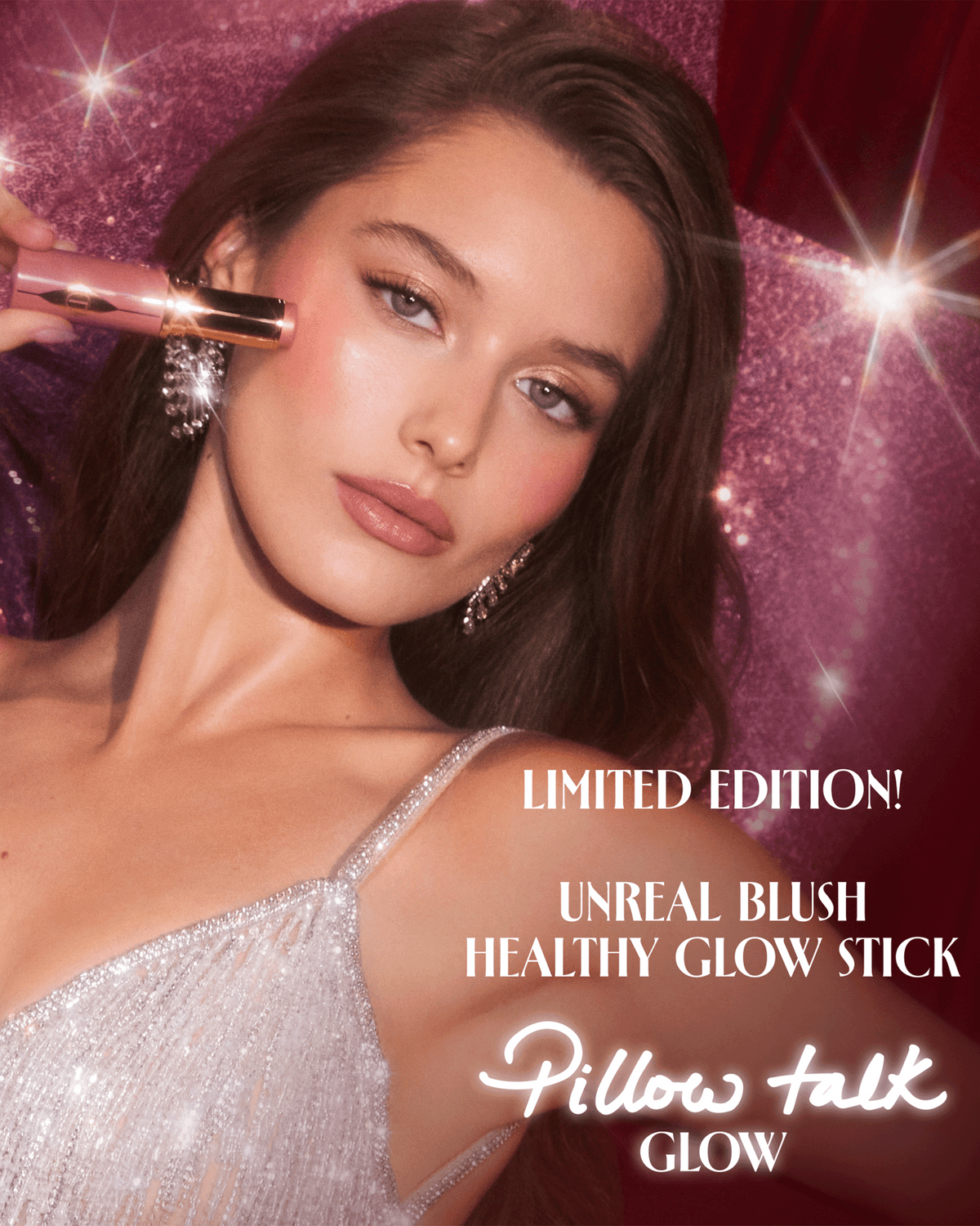 Model applying Charlotte Tilbury Pillow Talk blush stick against a sparkling pink backdrop.
