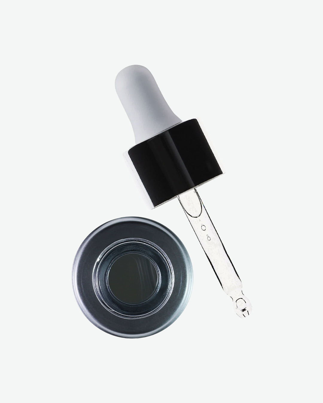 Glass dropper with black cap and clear liquid next to a small round container on a white background
