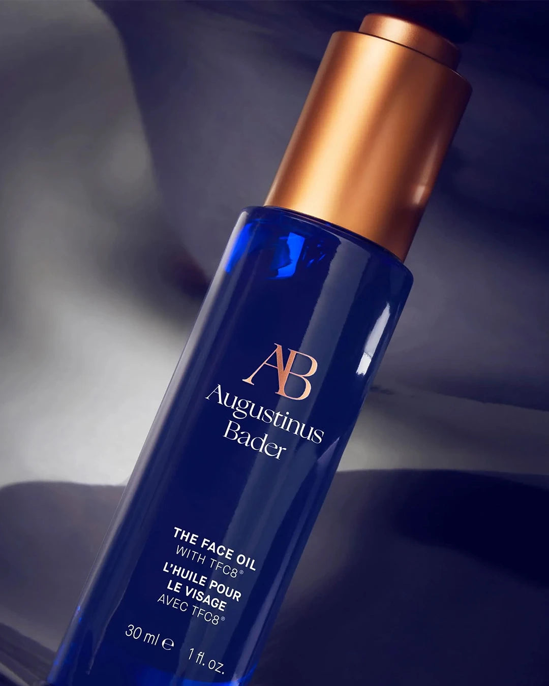 Blue skincare bottle with bronze cap on a dark background