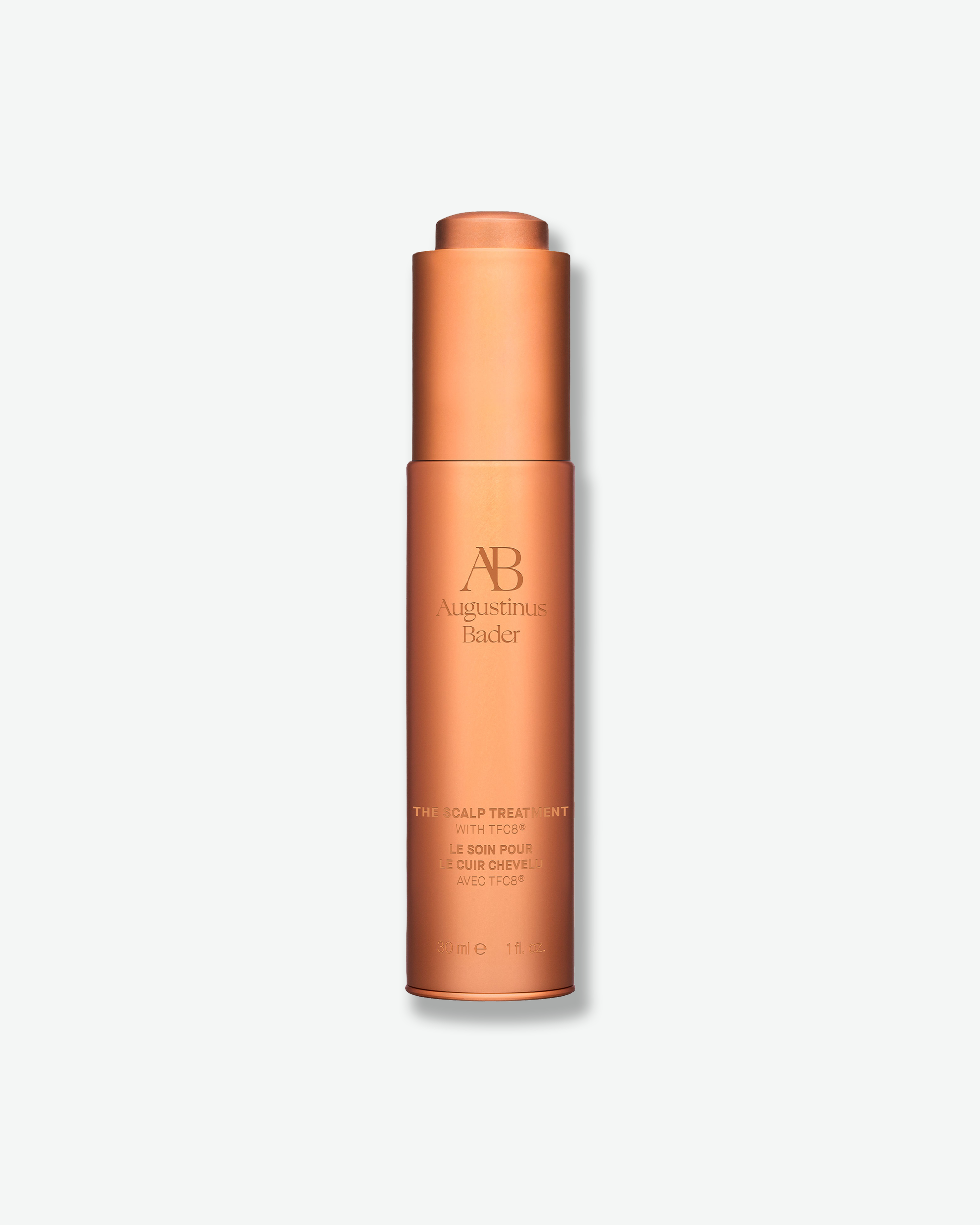 A tall, cylindrical copper-colored bottle of Augustinus Bader The Scalp Treatment with a built-in dropper top, centered on a light gray background.