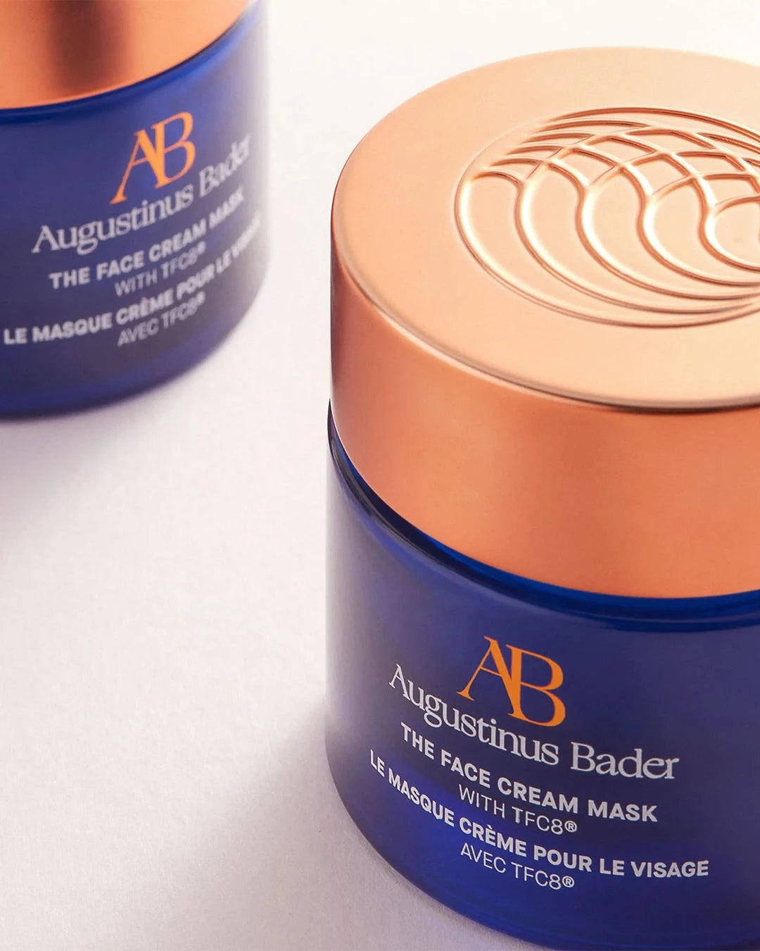 Two Augustinus Bader face cream masks with blue and orange packaging on a white background.