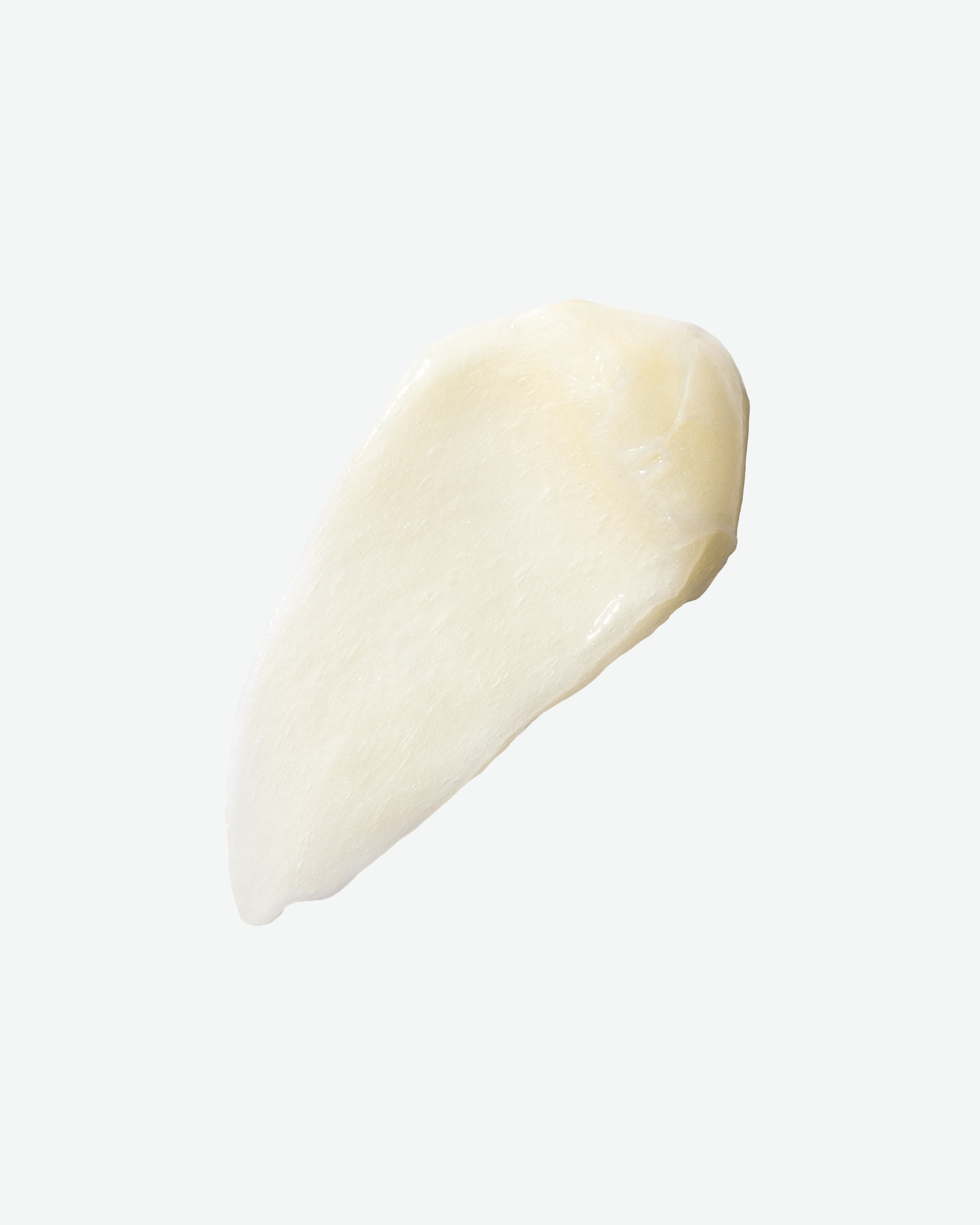 A top-down close-up view of a thick smudge of creamy, pale-yellow hair conditioner against a solid white background.