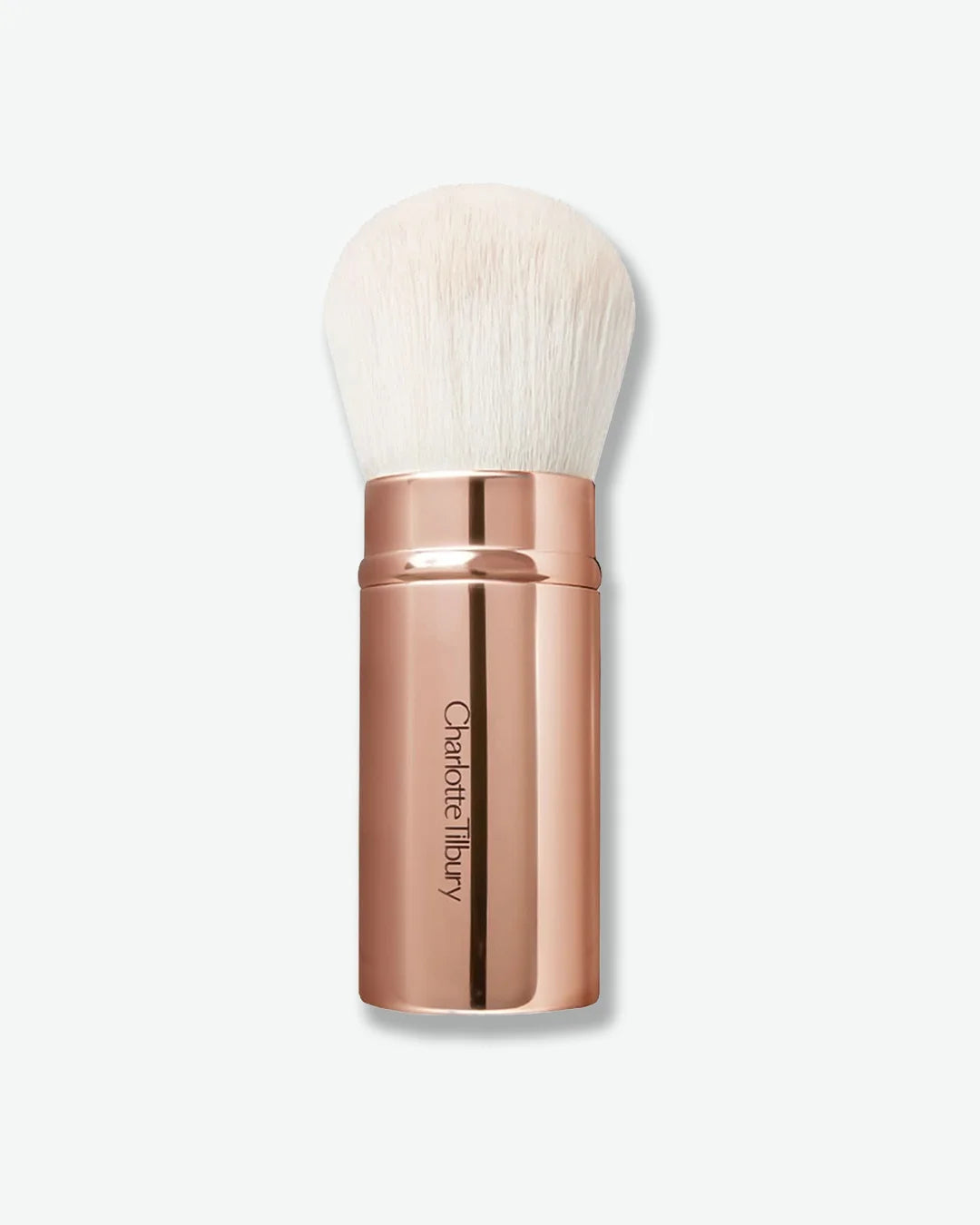 Rose gold makeup brush with white bristles on a light beige background