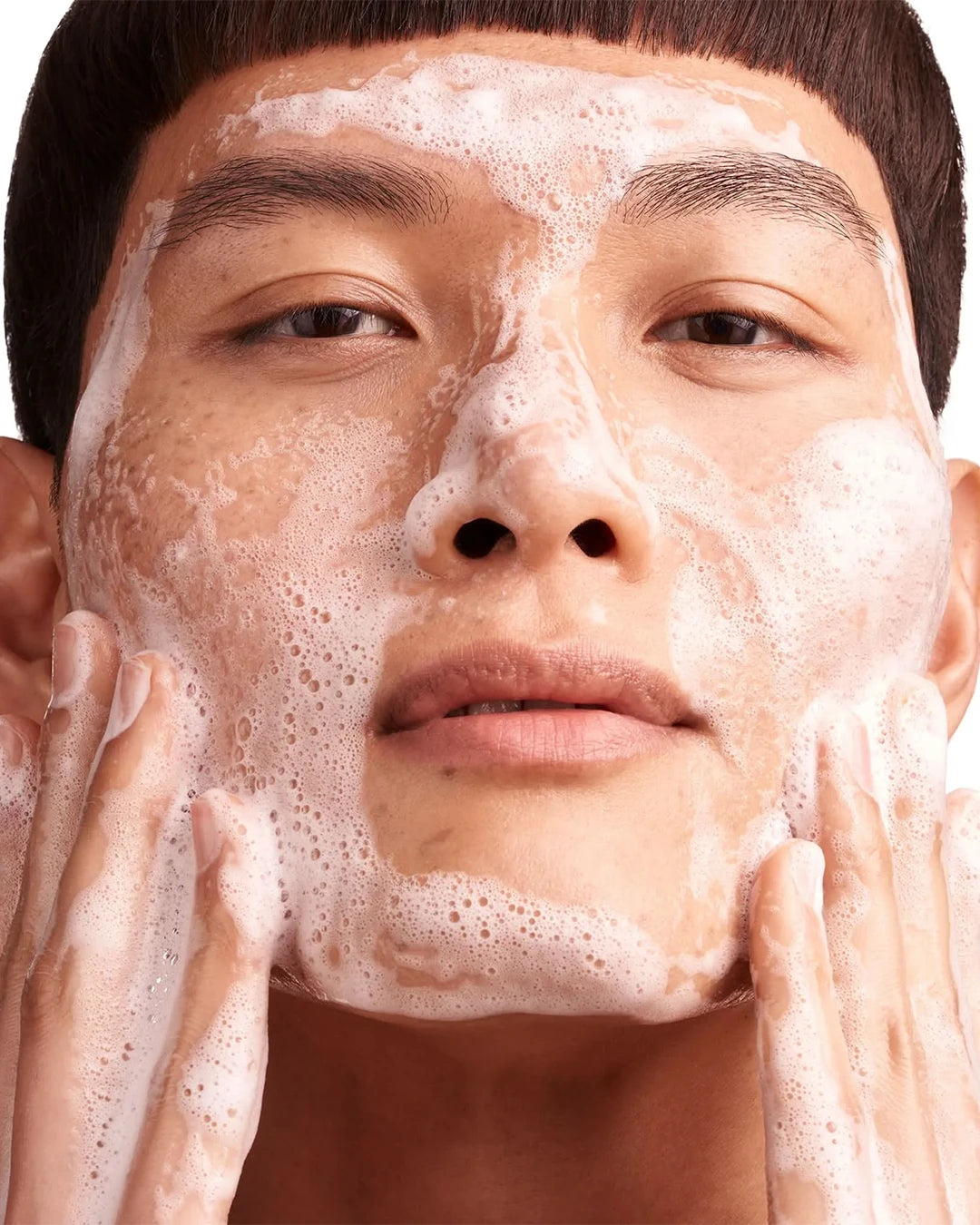 Person applying a foamy skincare product to their face