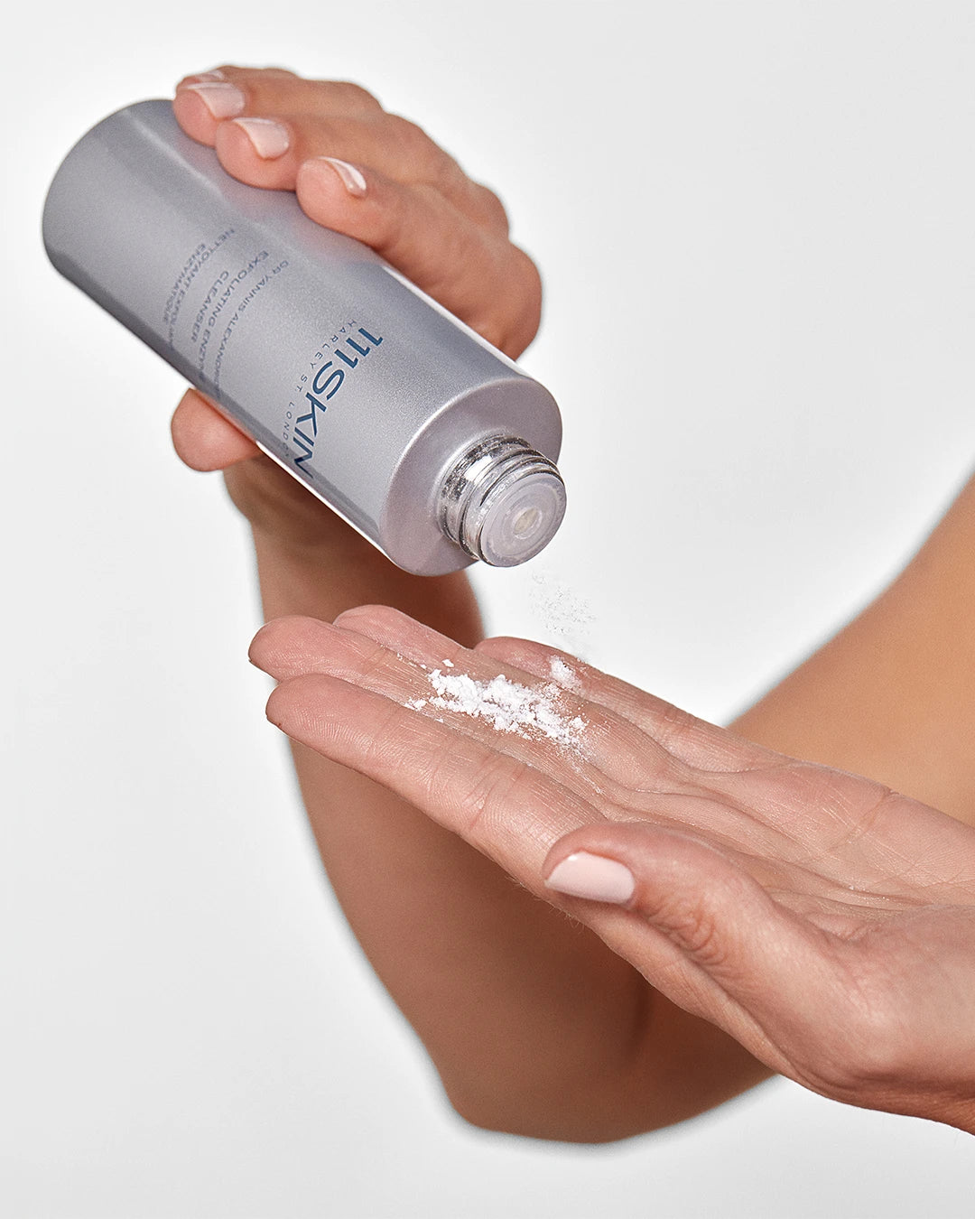 Person applying a white powder from a silver bottle labeled '111SKIN' on their palm.