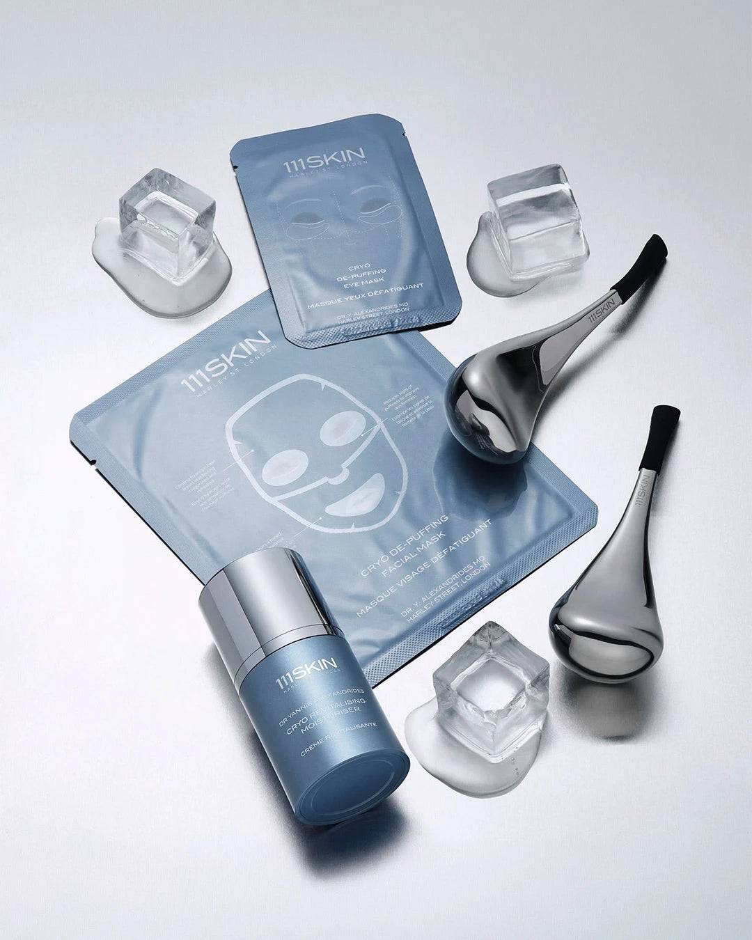 111SKIN skincare products including face masks, serum, and tools on a light gray background