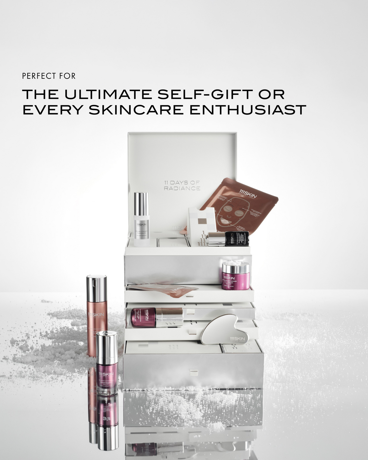 111SKIN 11 Days of Radiance holiday skincare set displayed open with serums, masks, moisturizer, and facial tool, designed as a luxe skincare gift.