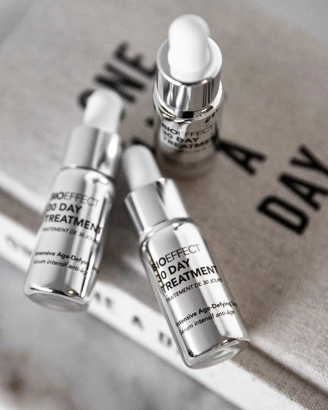 Three skincare serum bottles labeled '30 Day Treatment' on a textured surface.
