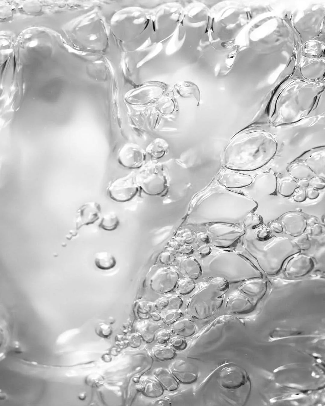 Close-up of clear liquid with bubbles on a light gray background