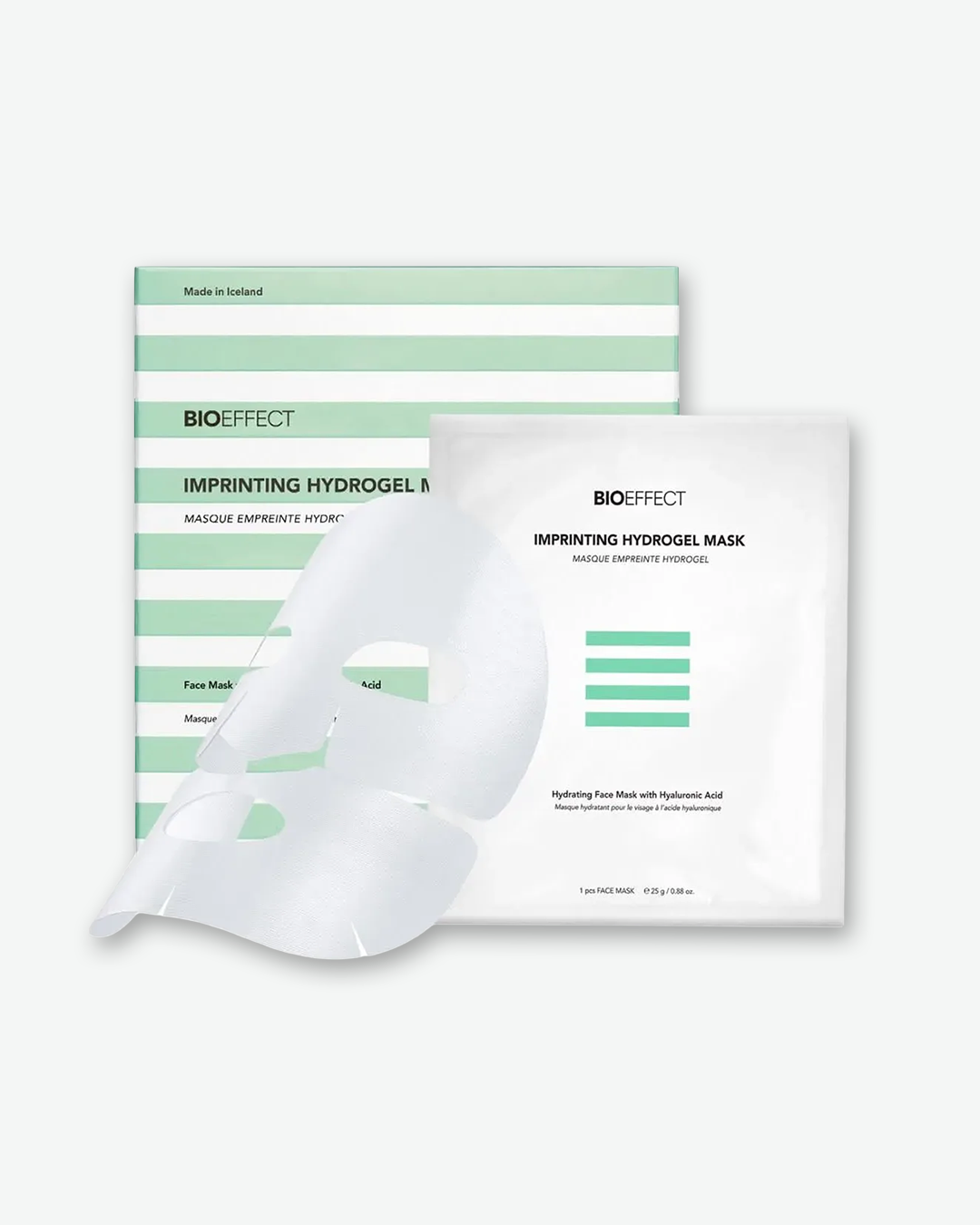 An unfolded translucent BIOEFFECT Imprinting Hydrogel Mask draped in front of a white single-use sachet and its green-and-white striped product box.